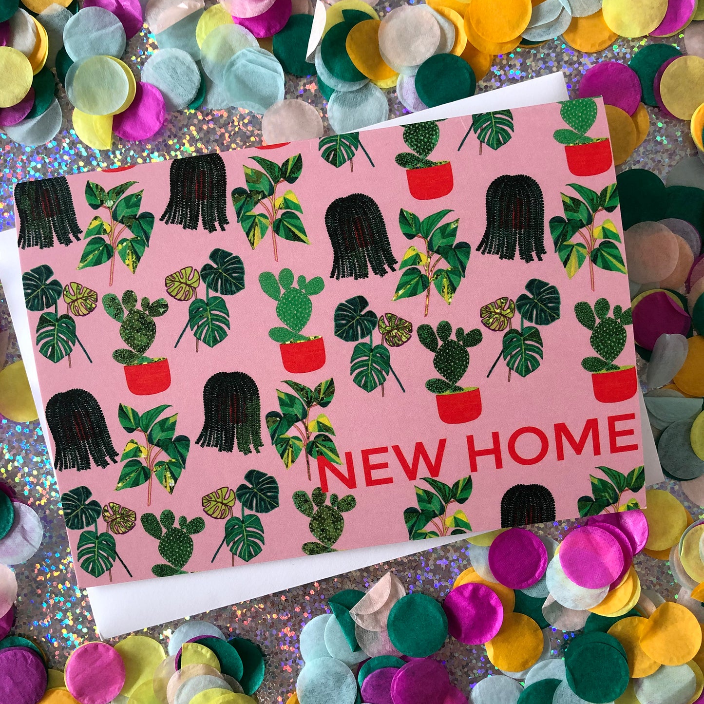 Image shows a pastel pink new home card with a pattern of illustrated green house plants and orange pots and writing.