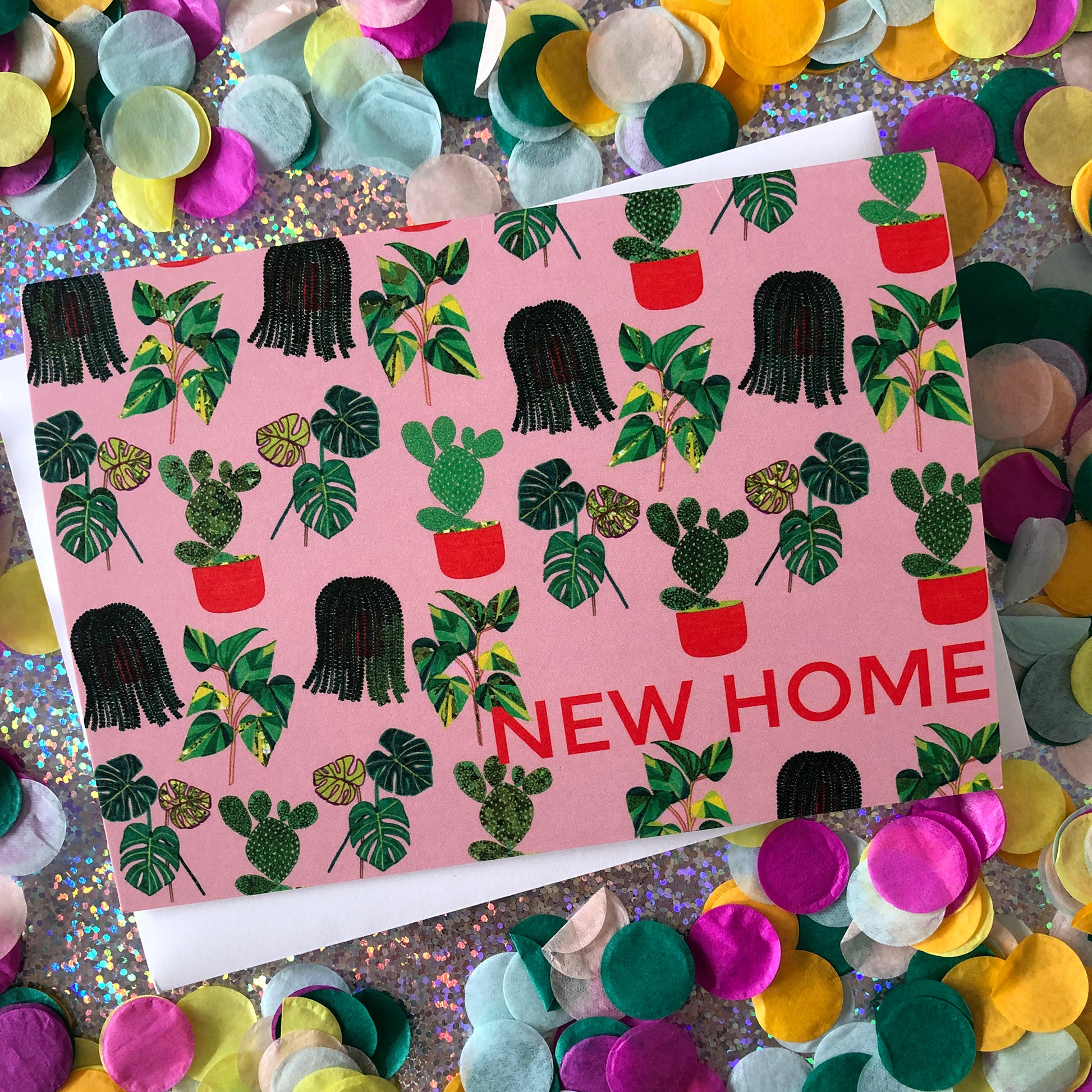 Image shows a pastel pink new home card with a pattern of illustrated green house plants and orange pots and writing.