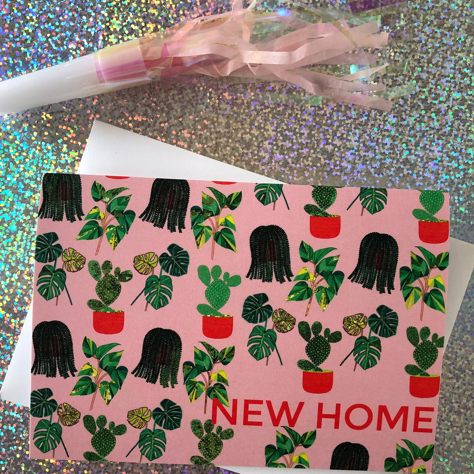 Image shows a pastel pink new home card with a pattern of illustrated green house plants and orange pots and writing.