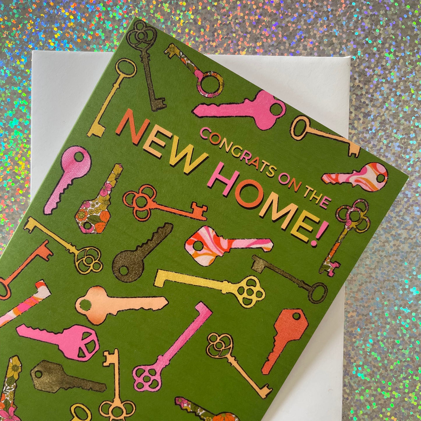 Image shows a green greetings card with a illustrations of colourful keys and the words 'Congrats on the new home'