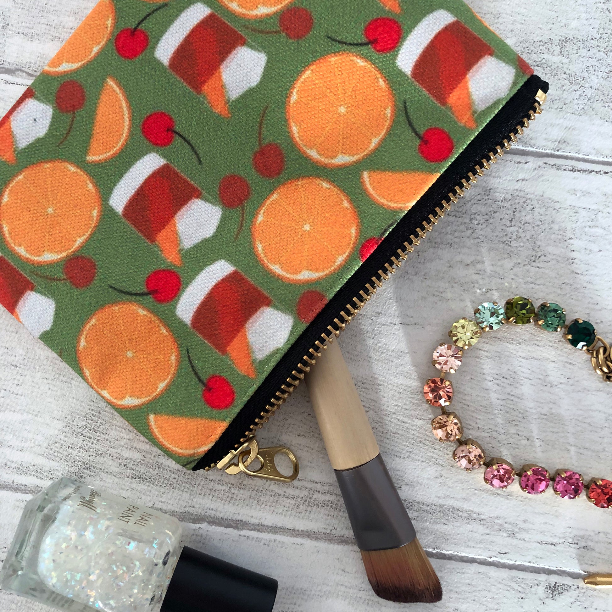 Image shows a handy zip pouch featuring a fun retro old fashioned cocktail inspired design
