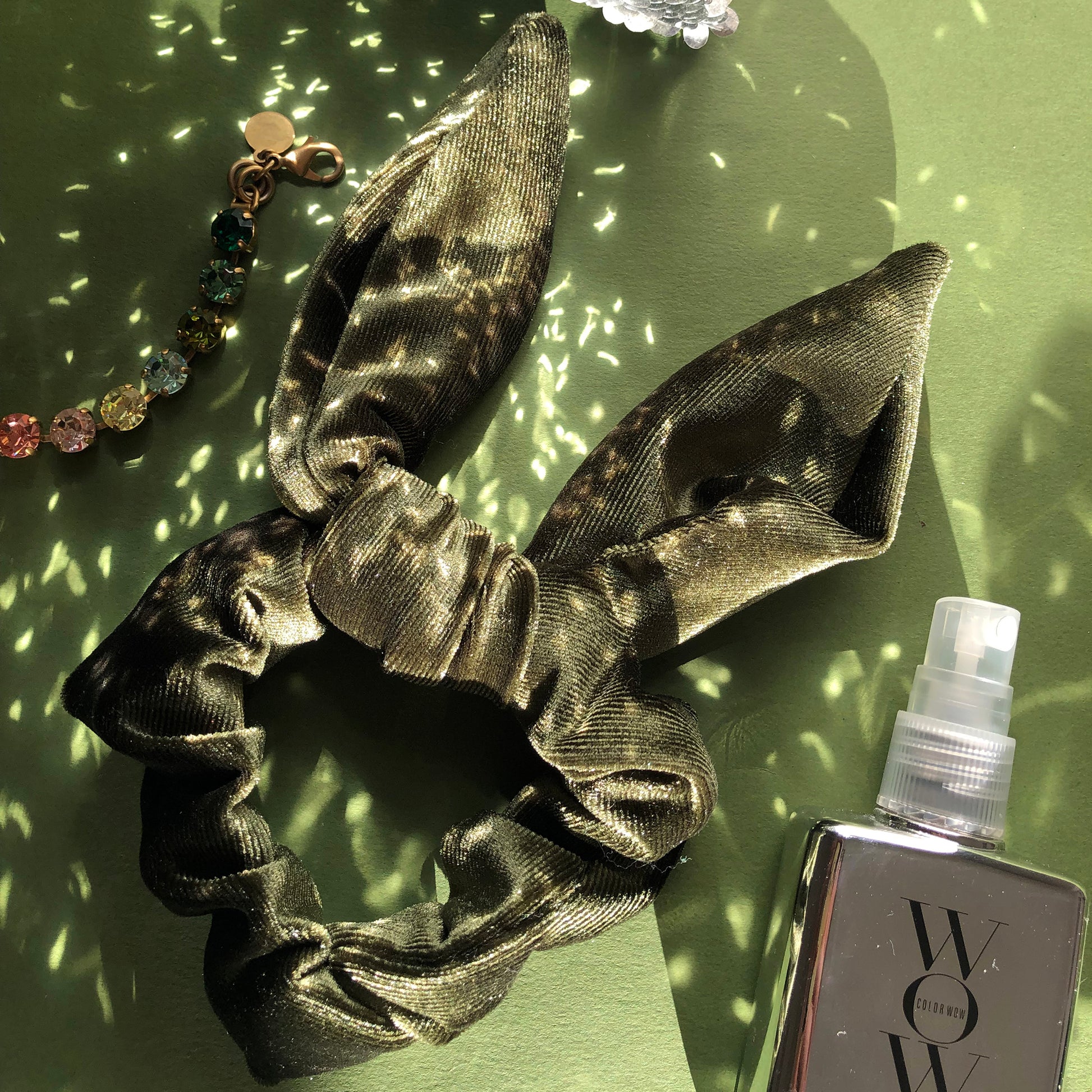 Image shows an olive green velvet hair scrunchie with a knot and bow