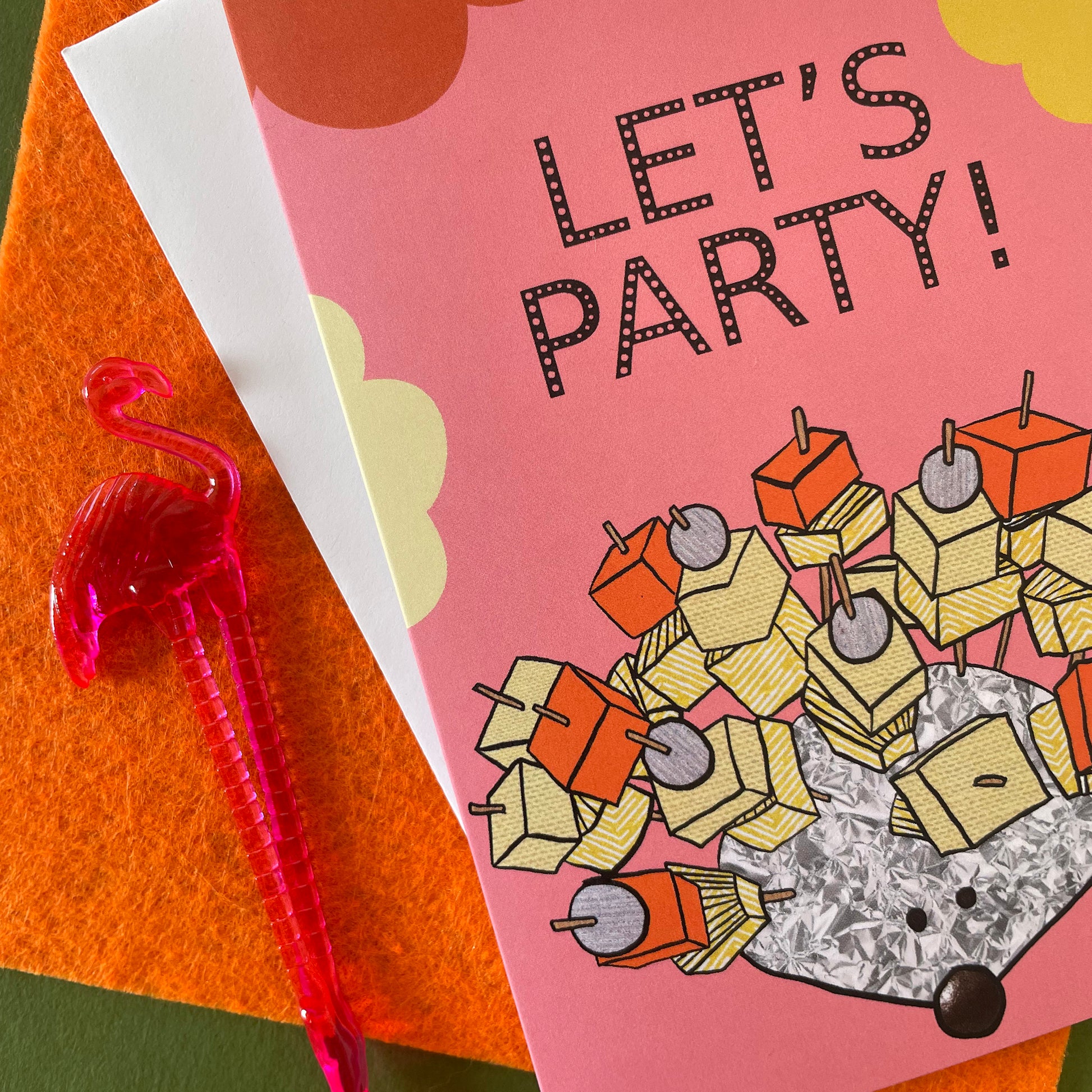 Image shows a pink greetings card with an illustration of a silver foil 'party hedgehog' with cheese, pineapple and pickled onions on cocktail sticks and the words 'let's party'