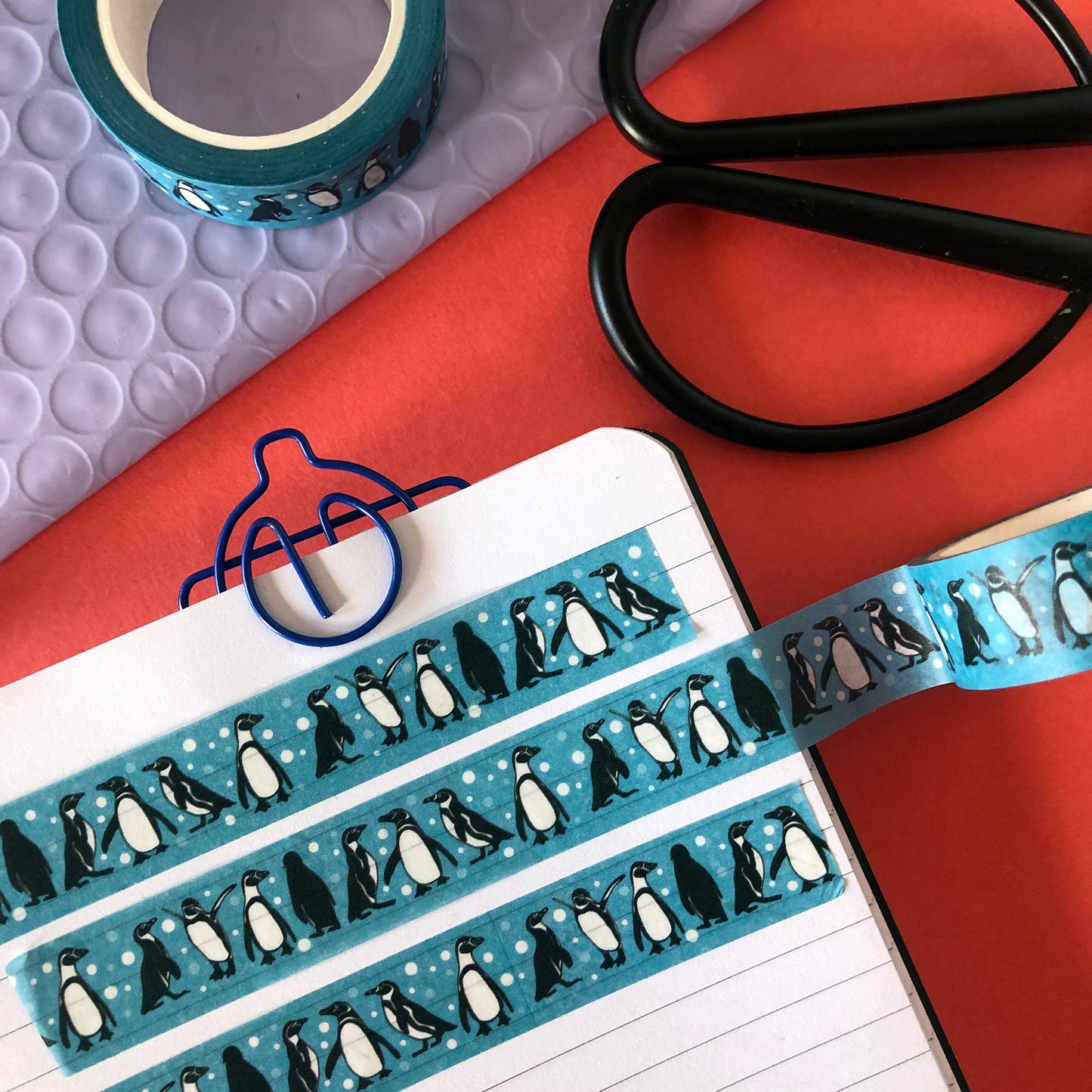 Image shows a blue washi tape with a fun penguin and snowball print