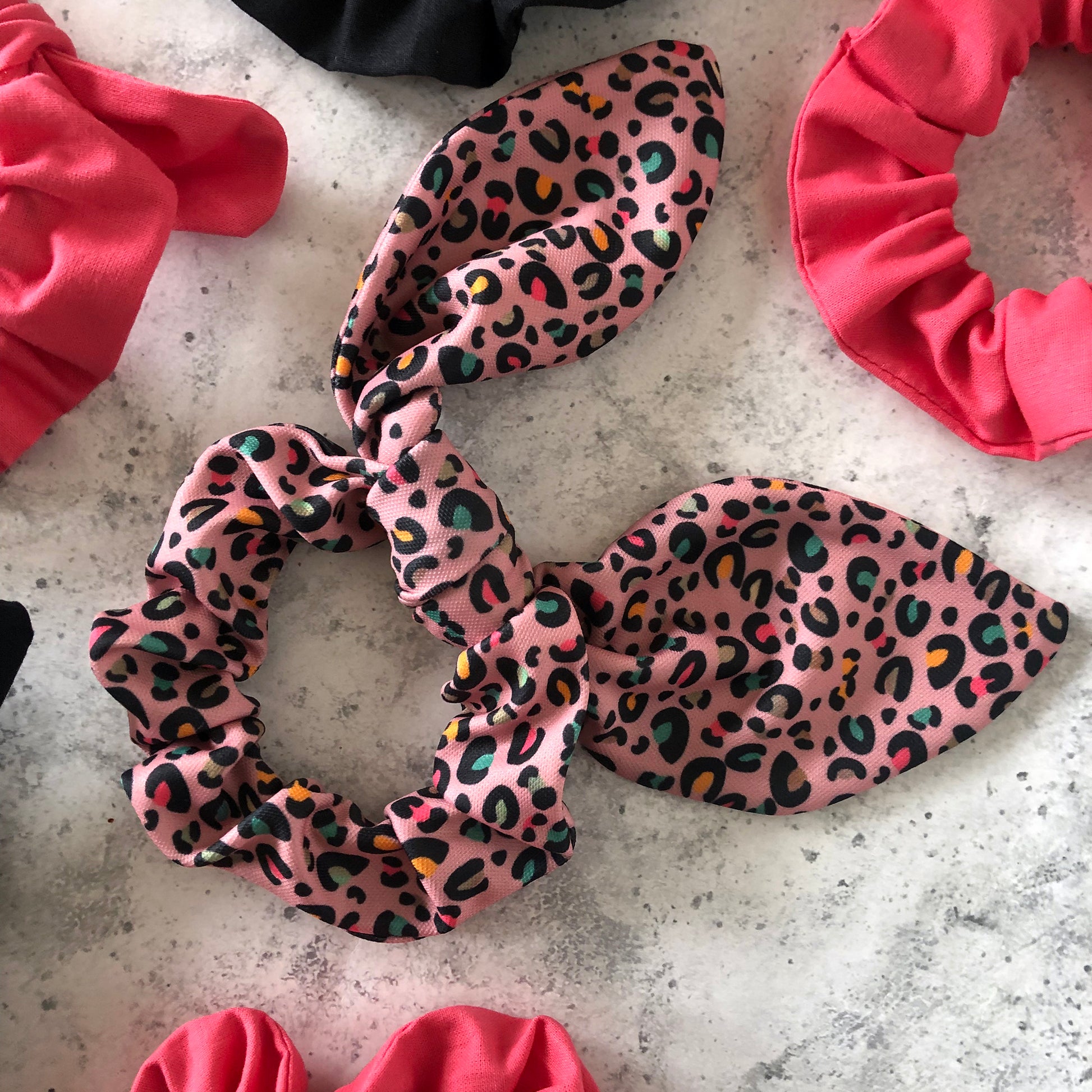 Image shows a pink leopard print hair scrunchie with a knot and bow
