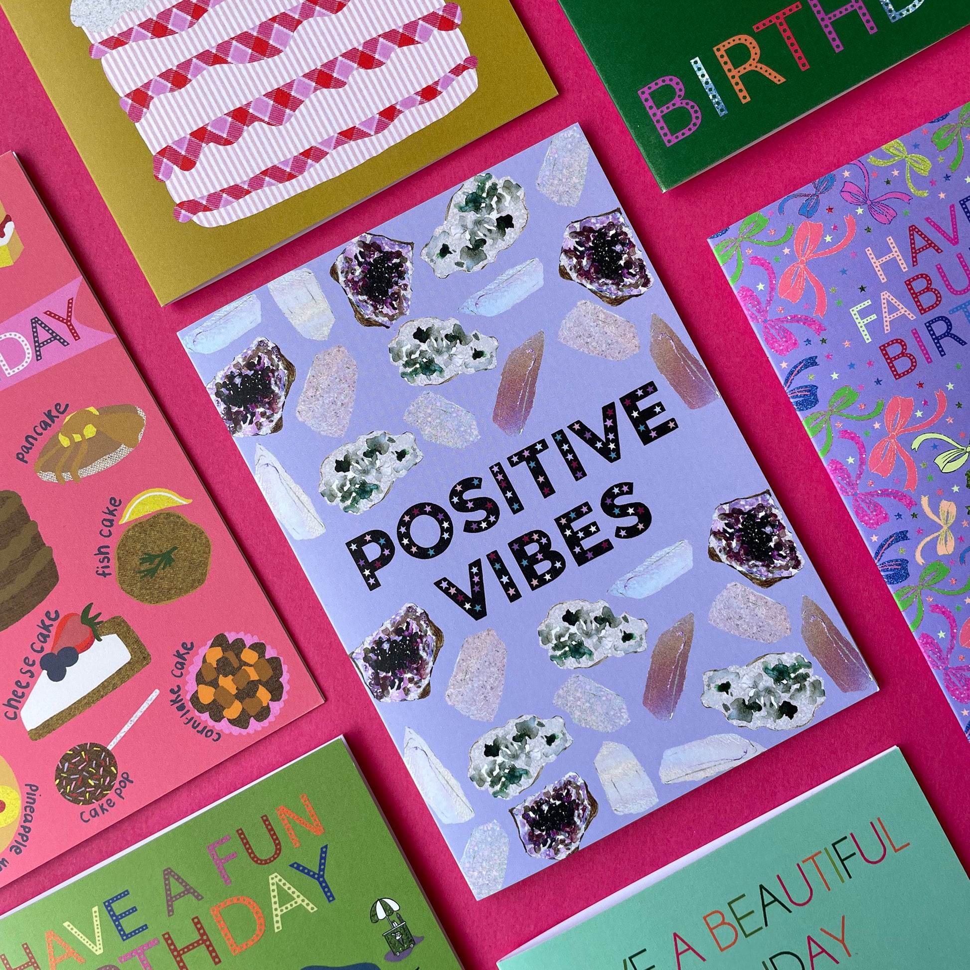 Image of a lavender coloured greetings card with illustrations of crystals and the words 'Positive Vibes'