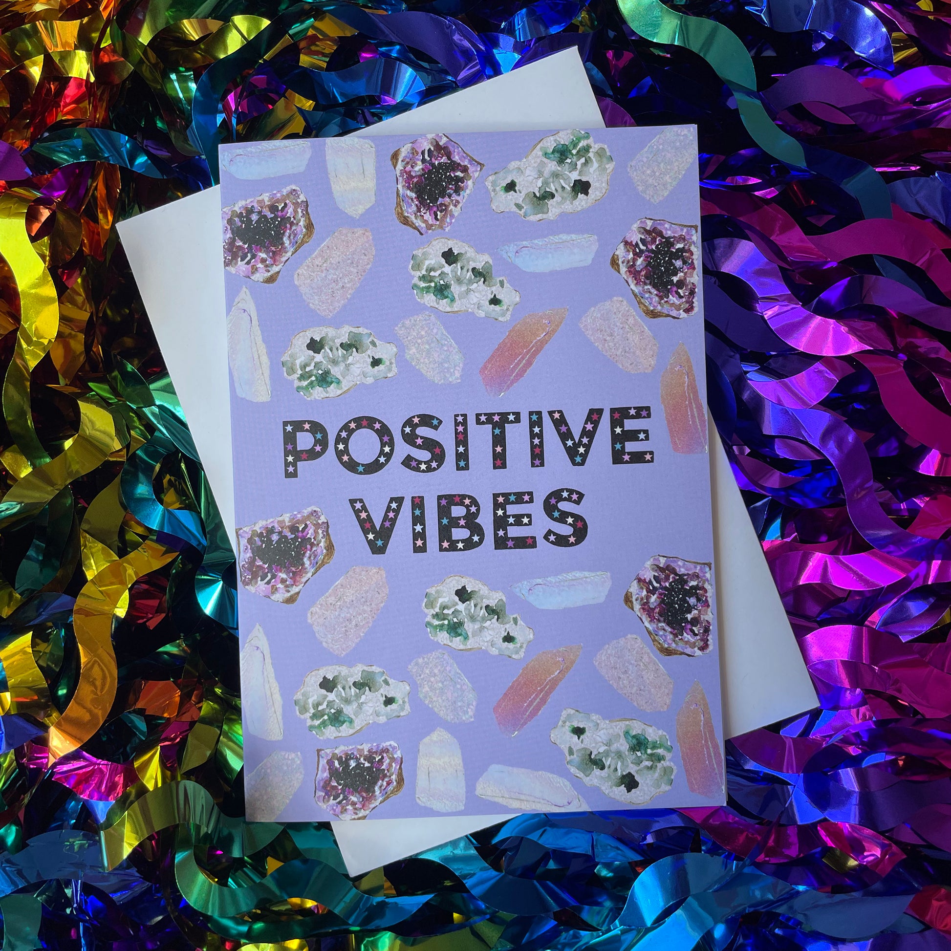 Image of a lavender coloured greetings card with illustrations of crystals and the words 'Positive Vibes'