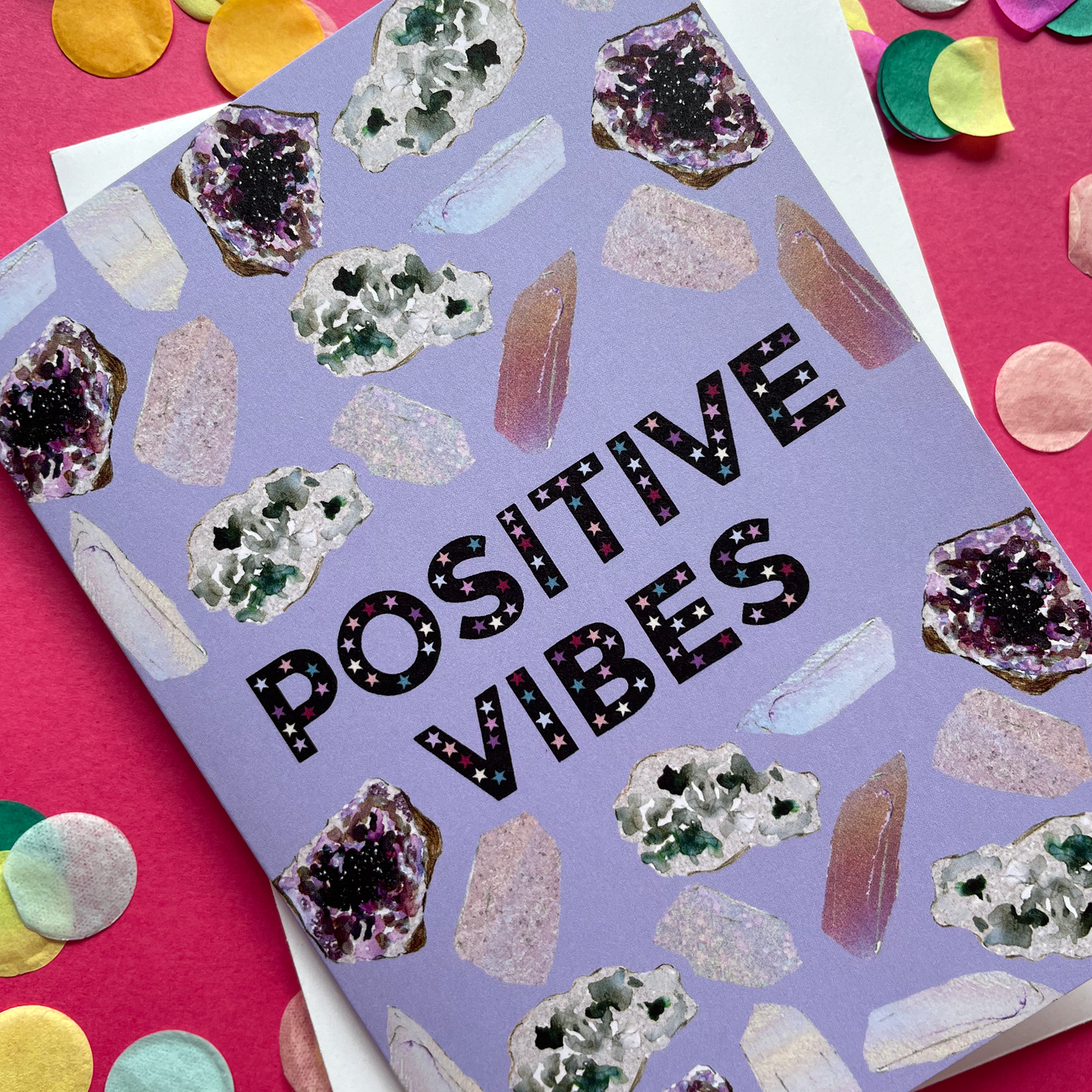 Image of a lavender coloured greetings card with illustrations of crystals and the words 'Positive Vibes'