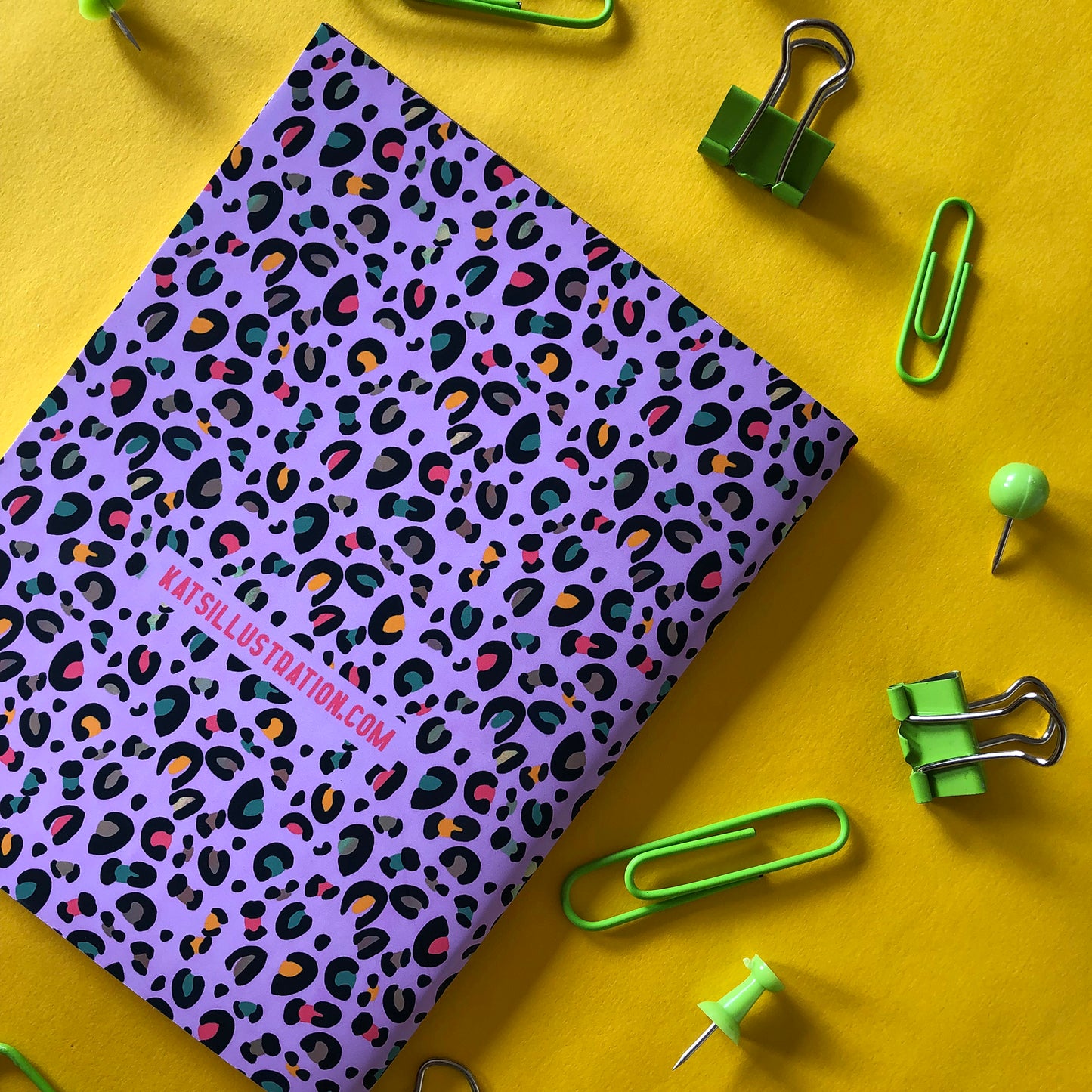 Image shows an A6 notebook in a bright purple with a leopard print pattern featuring pops of neon
