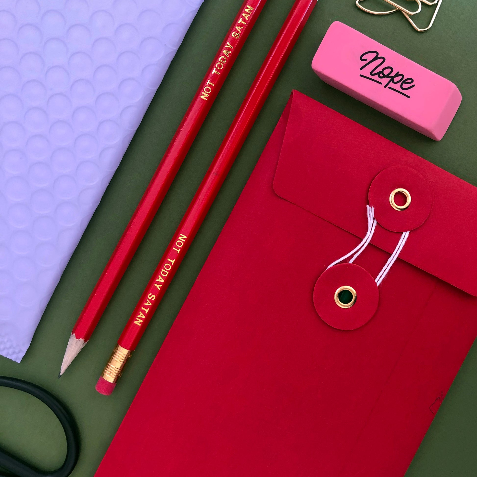 Image of a pencil in bright red with lettering embossed in gold with the wording 'not today satan'