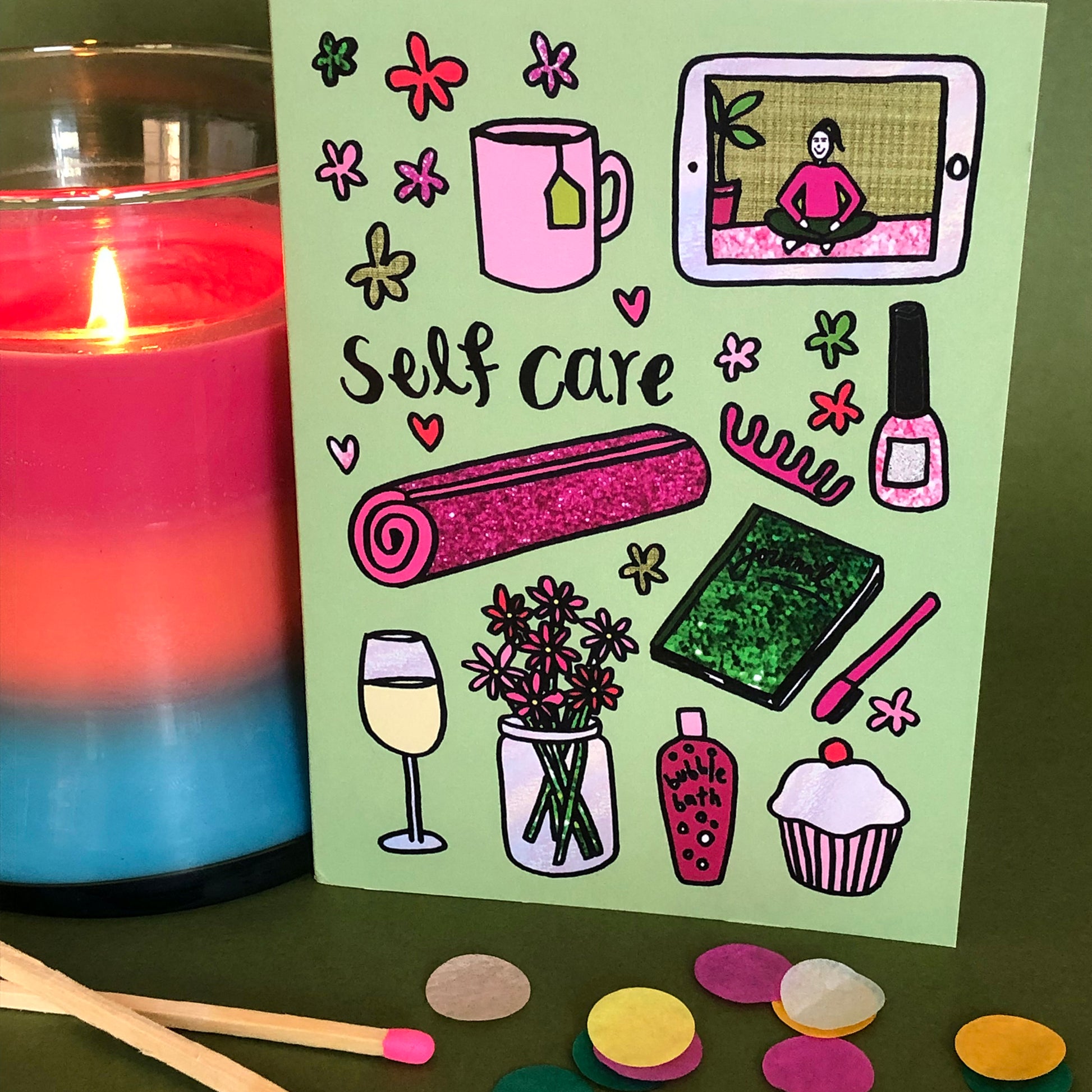 Image show a green greetings card that says 'self care' and features a fun pattern of self care items