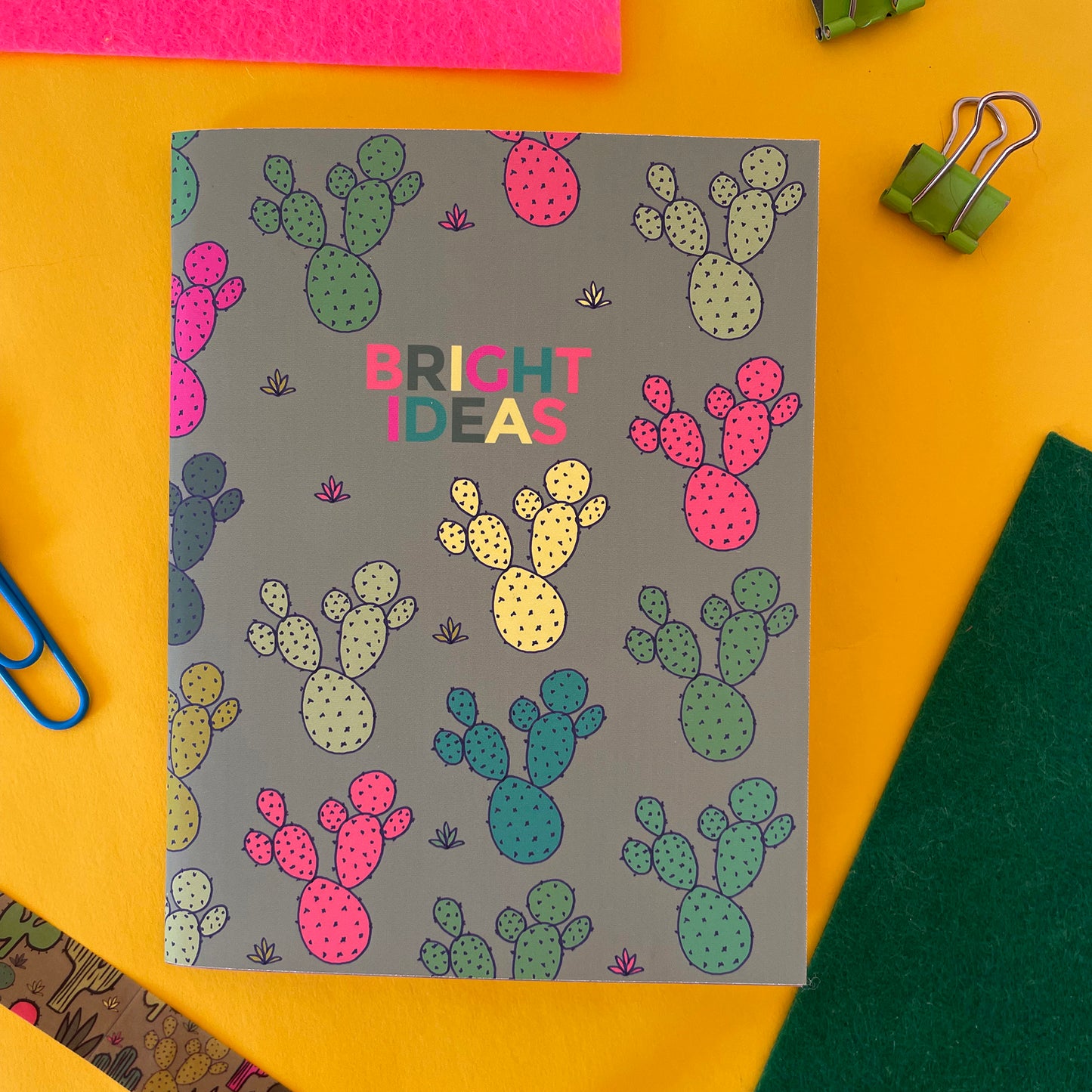 Image shows a pocket size green notebook with a neon cactus print and 'Bright Ideas' written on the front.