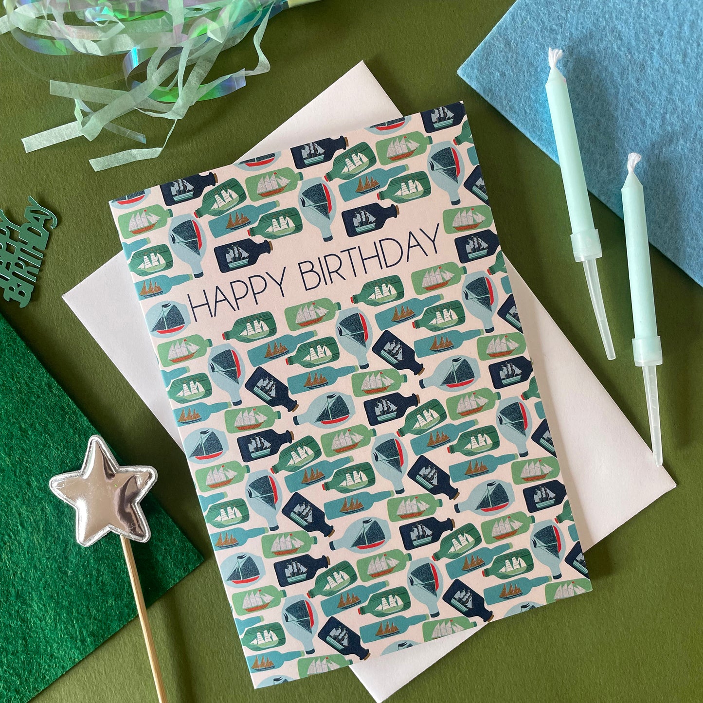 Image shows a birthday card with the greeting 'Happy Birthday' and an illustrated ships in bottles pattern.