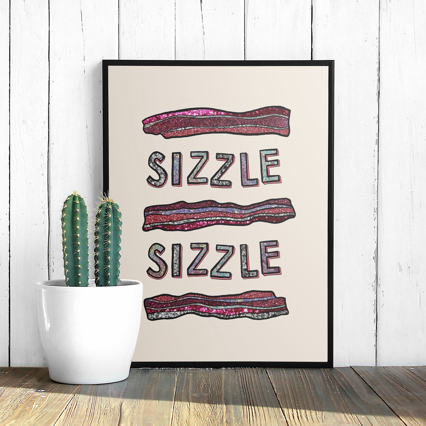 Image of a framed art print of a modern illustration glittery bacon and the words Sizzle Sizzle.