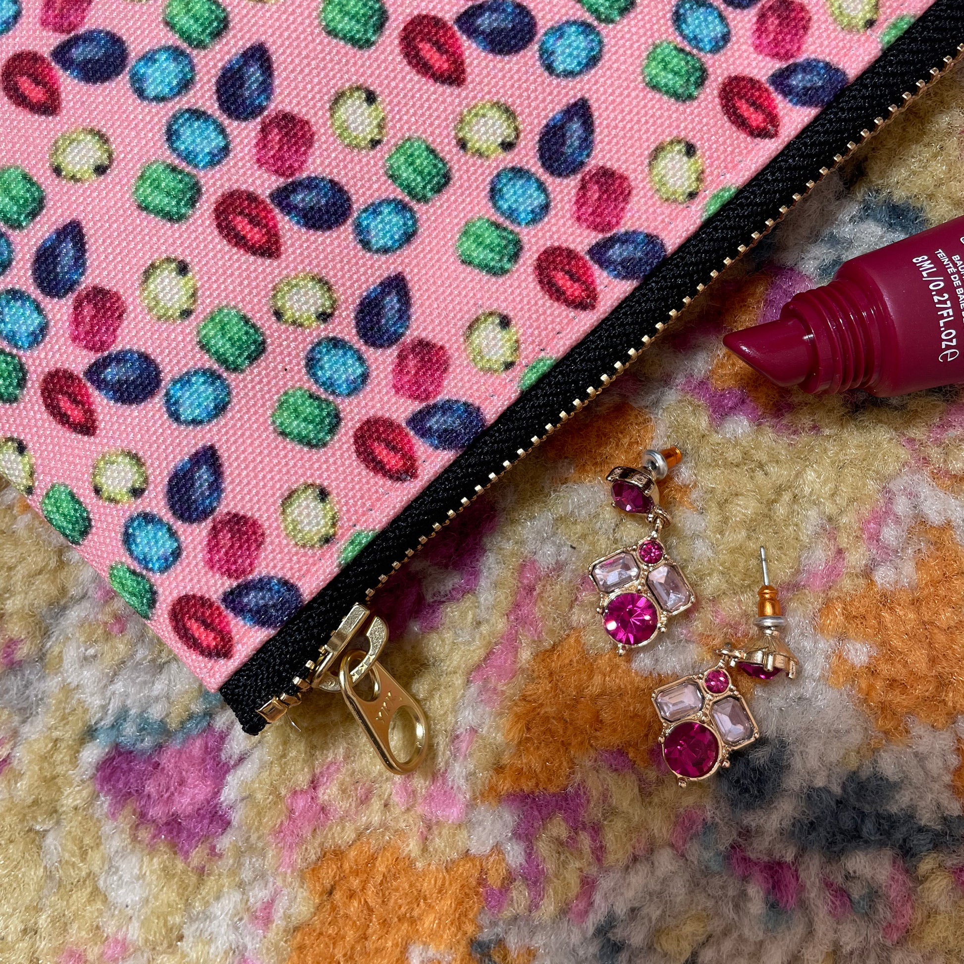 Image shows a handy zip pouch in pastel pink featuring a unique colourful gemstone pattern