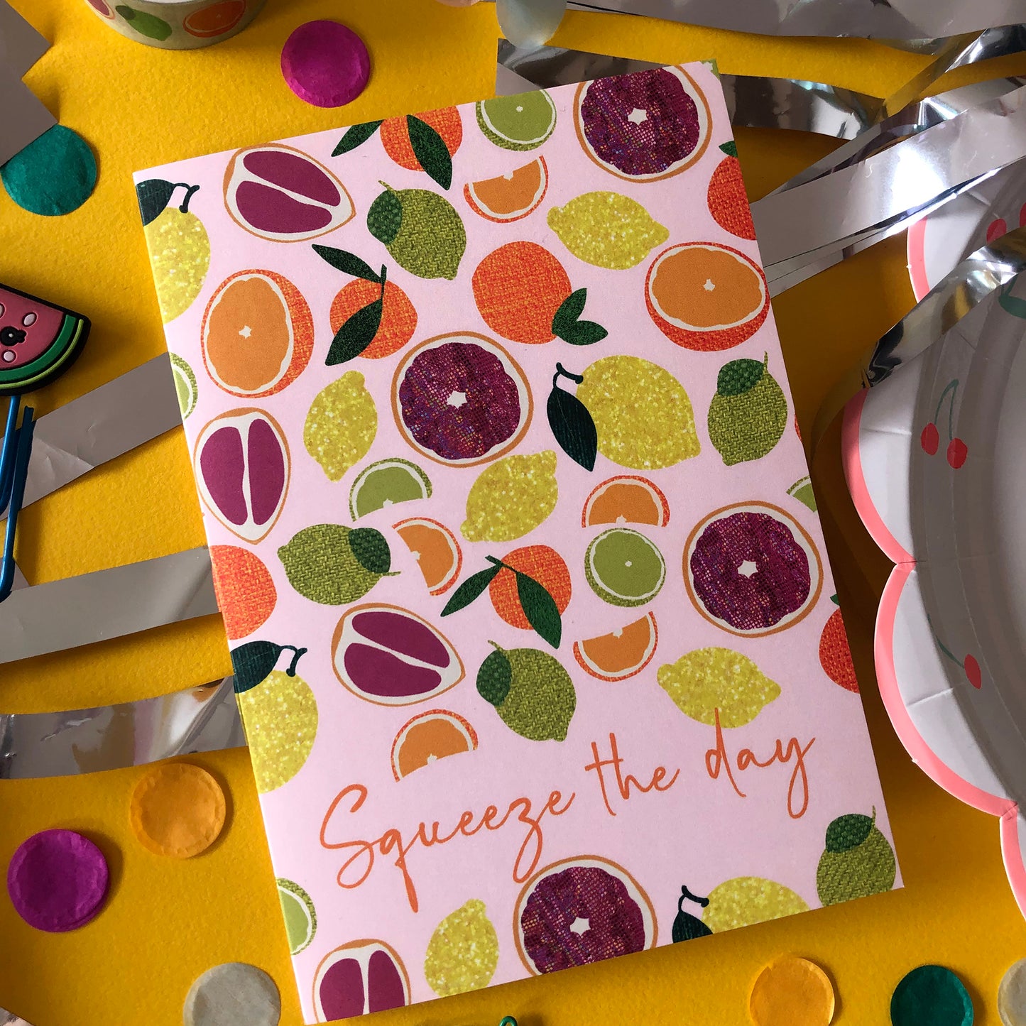 Image shows an everyday greetings card that says 'squeeze the day' and features a fun pattern of lemons, oranges, tangerines and grapefruit