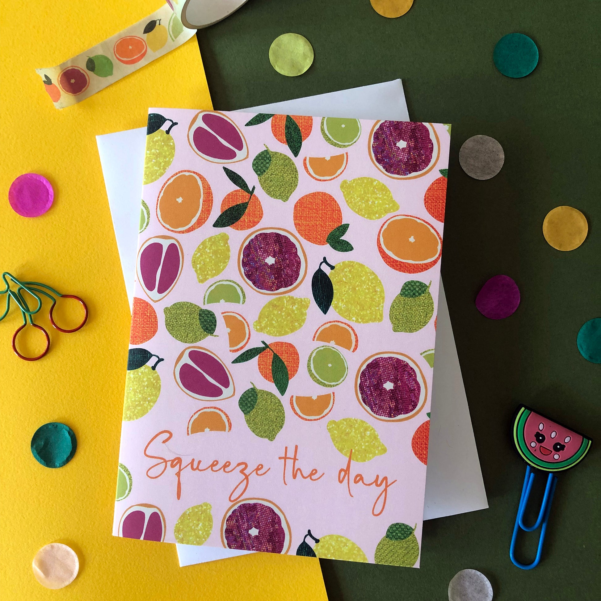 Image shows an everyday greetings card that says 'squeeze the day' and features a fun pattern of lemons, oranges, tangerines and grapefruit