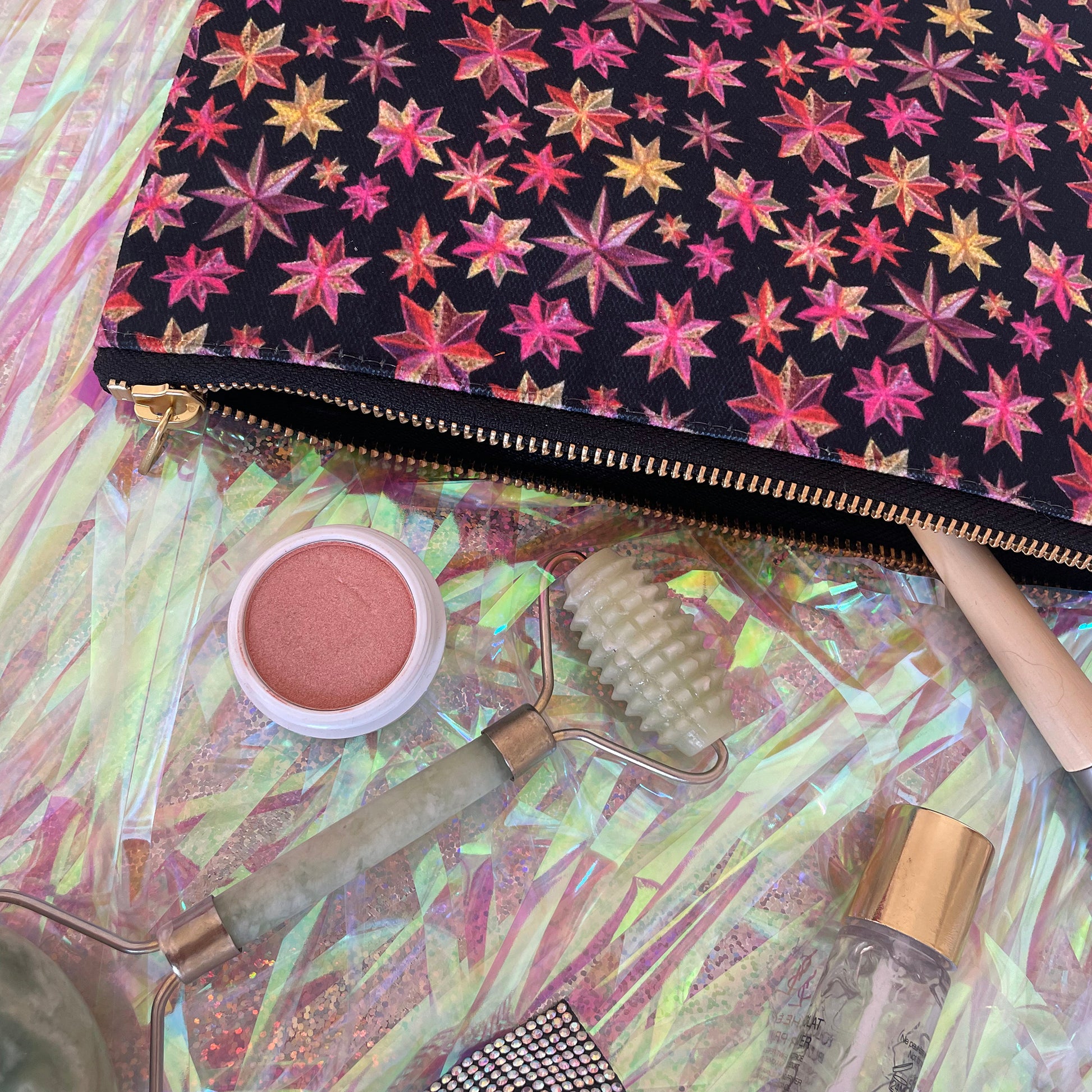 Image shows a black zip pouch with a bright pink, orange and gold starlight lantern design.
