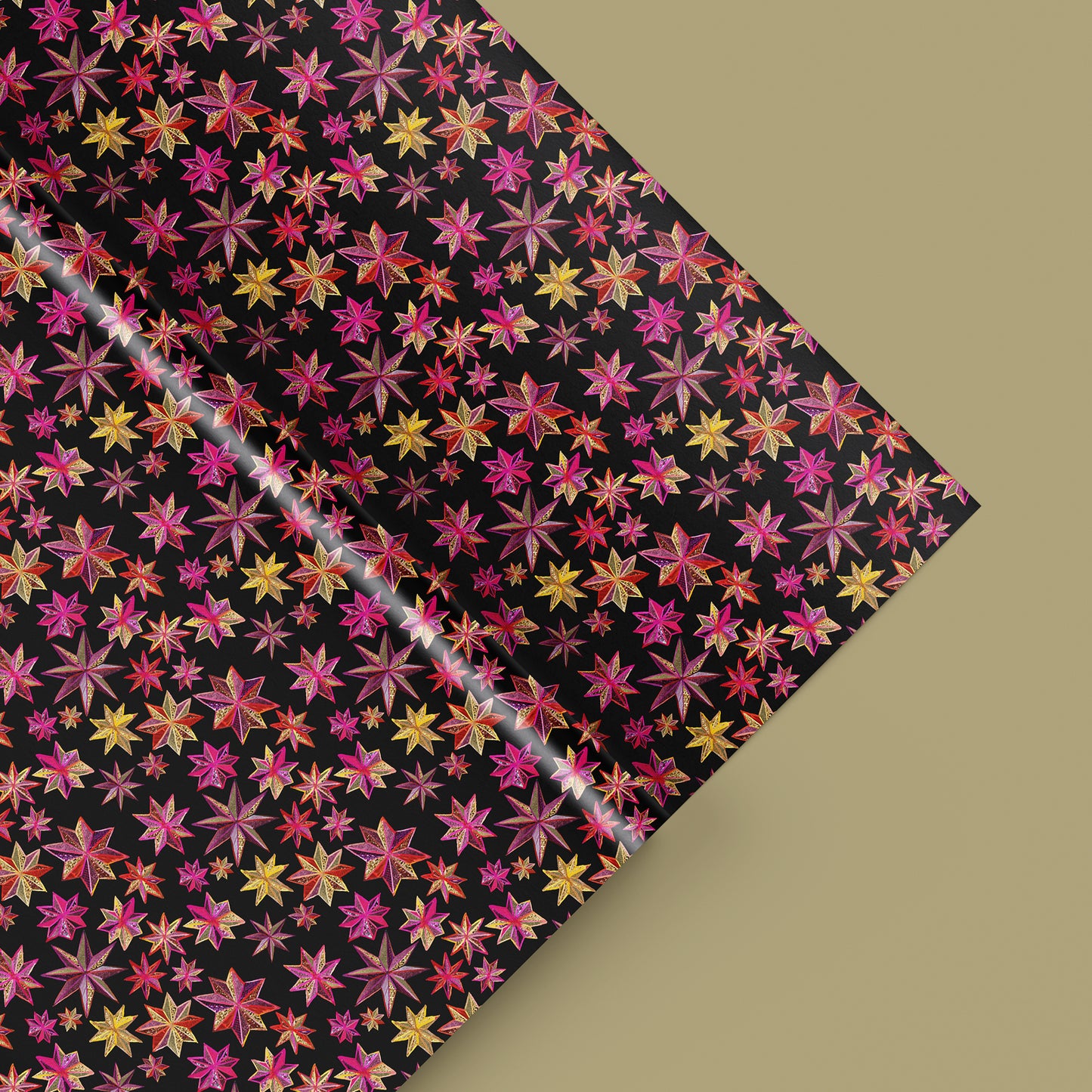 Image shows a gift wrap sheet in black with a bright pink and gold folk art star pattern.