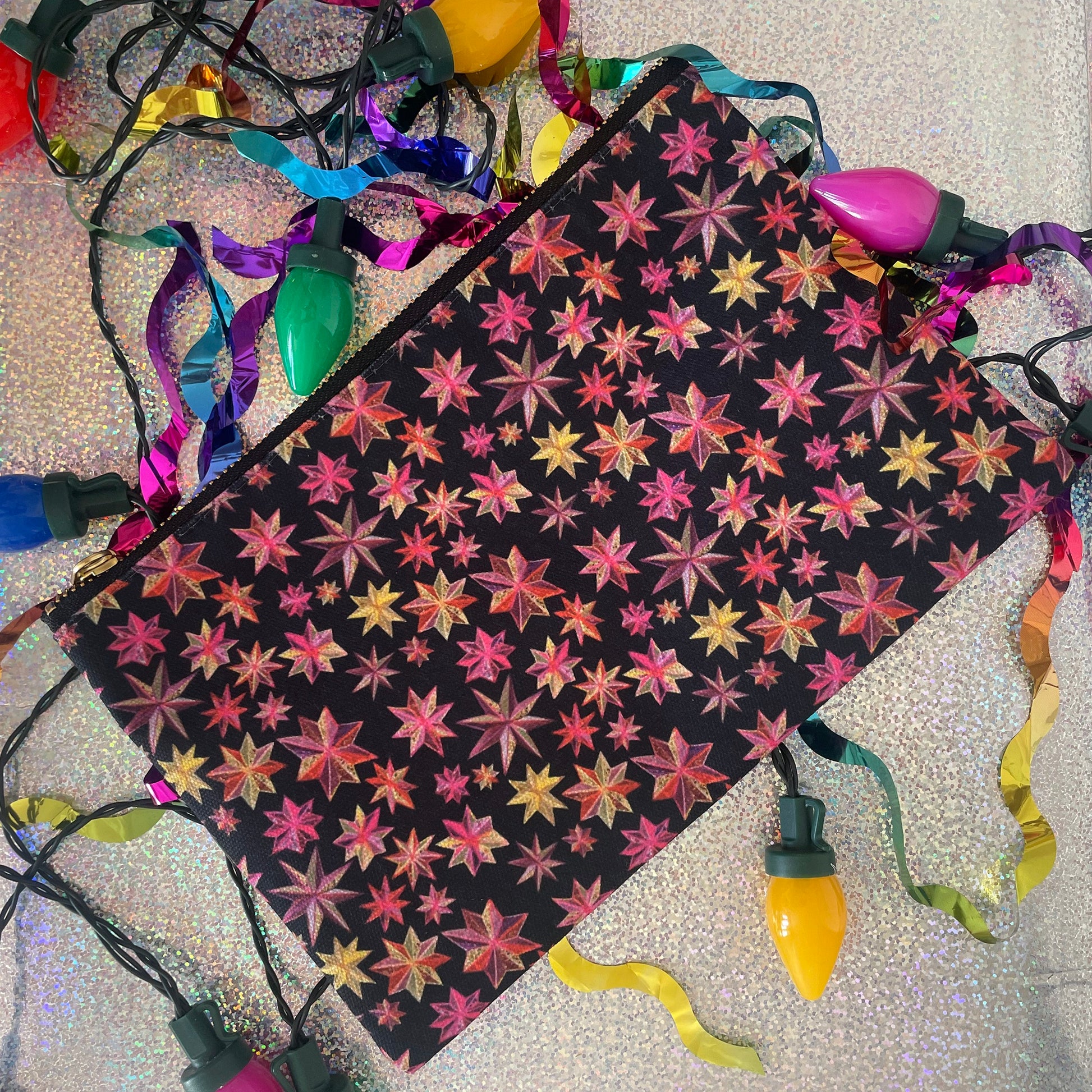 Image shows a black zip pouch with a bright pink, orange and gold starlight lantern design.
