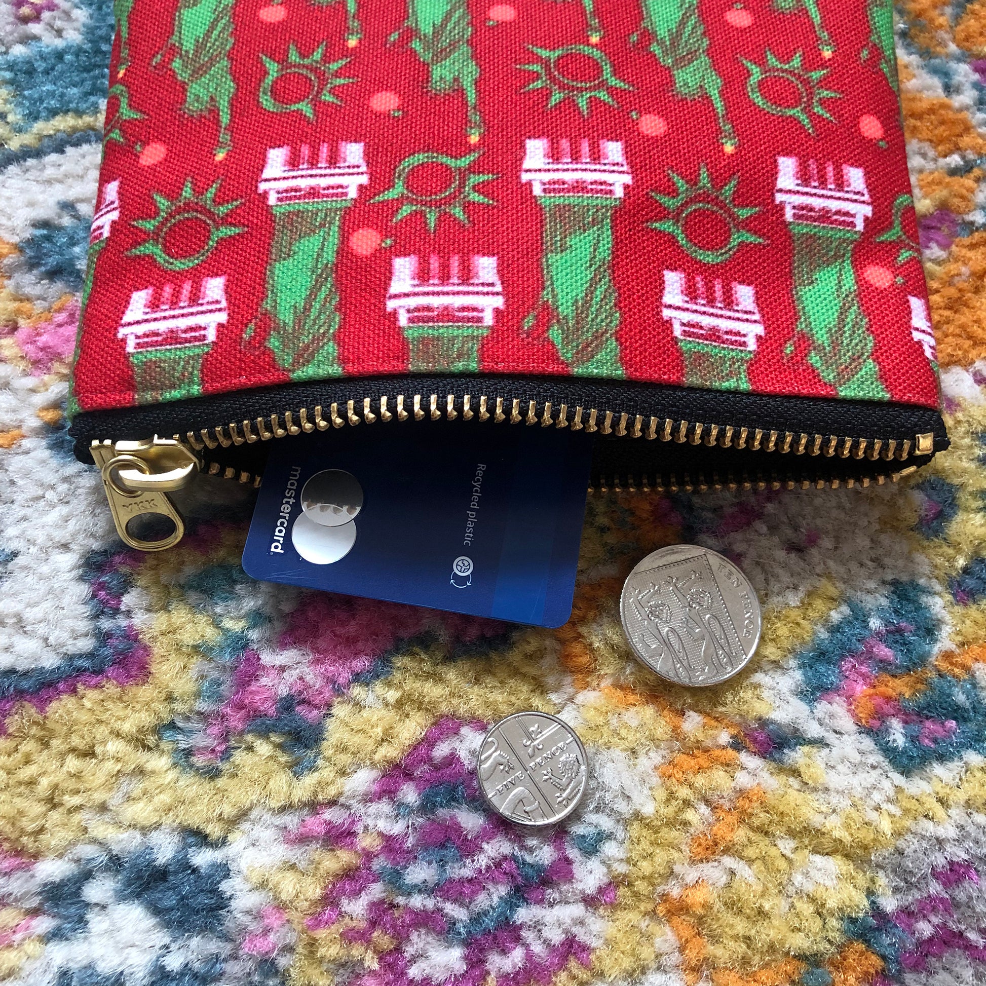 Image shows a handy zip pouch in a bold red colour with a statue of liberty pattern in green and white.
