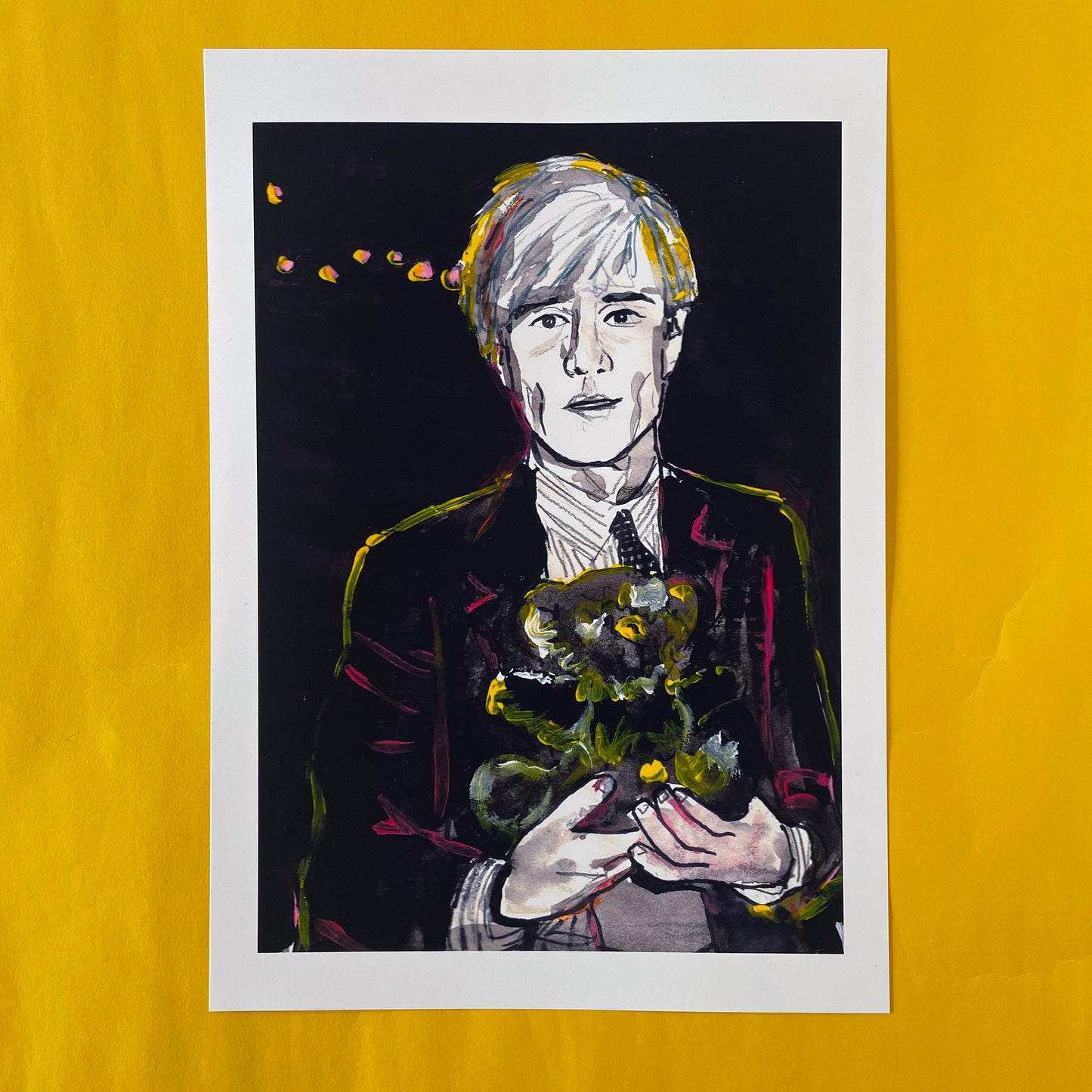 Image shows a framed portrait of artist Andy Warhol holding a teddy bear. The artwork is painted in black and white with neon pink and yellow highlights.