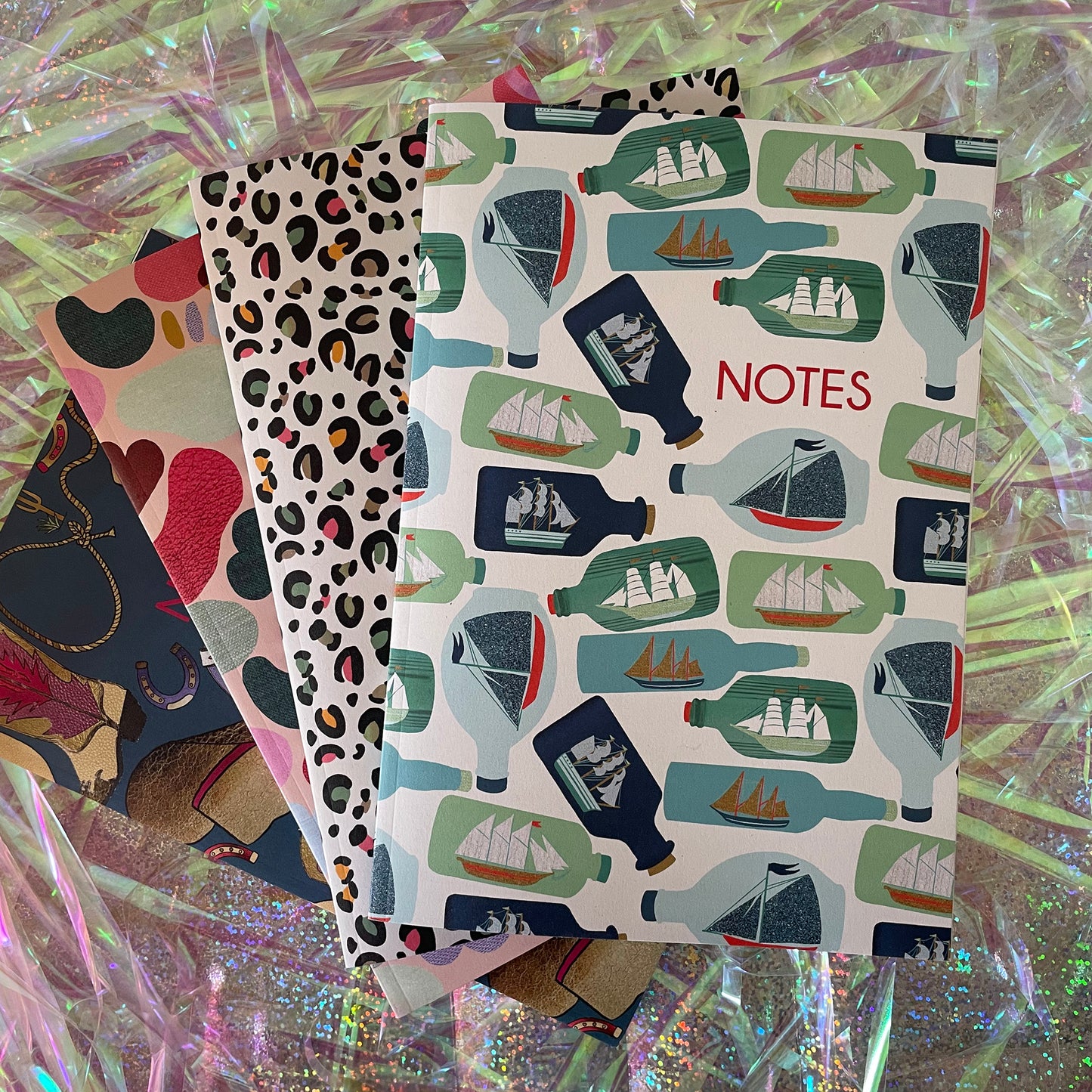 Image of a ships in bottles print A5 size notebook in a cream colour with blue and green bottles.