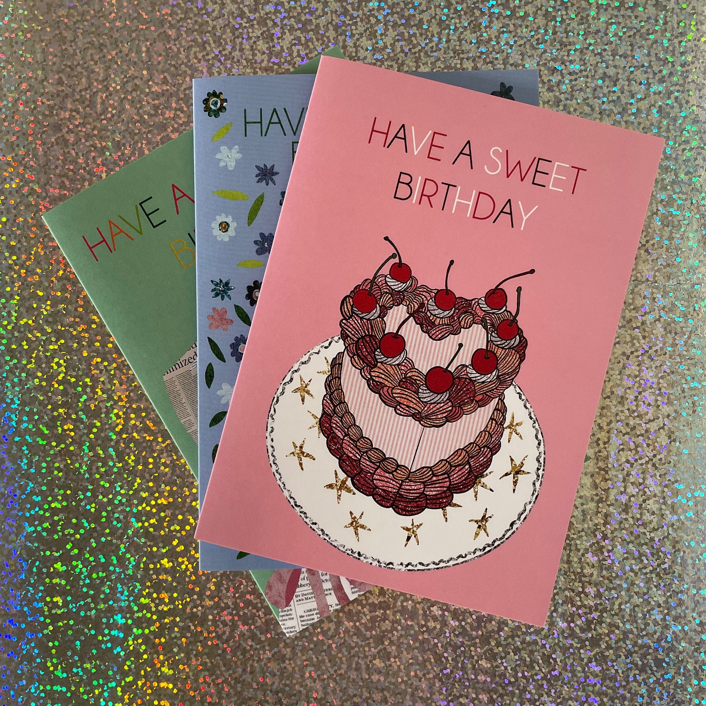 Image of a candy pink birthday card which says Have a Sweet Birthday and features a heart shaped cake with cherries on top