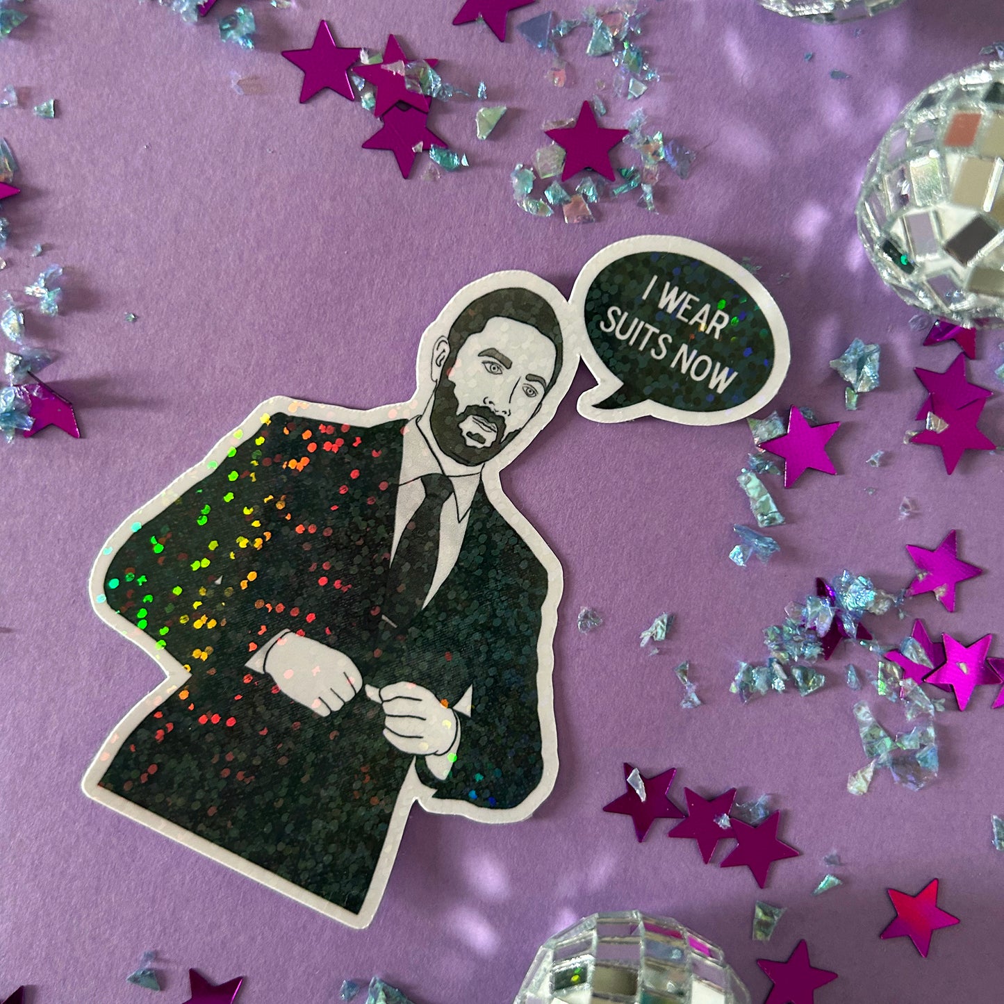 Sticker of a person wearing a suit with a speech bubble saying 'I wear suits now' on a purple background with stars and confetti.