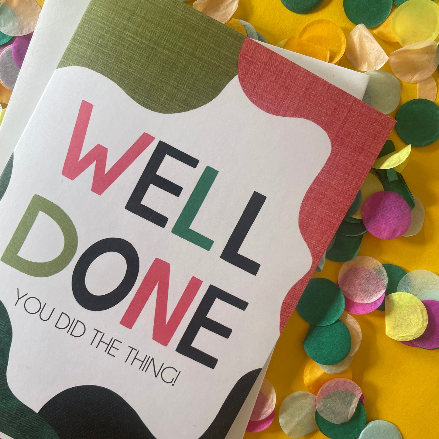 Image shows a bright greetings card with colourful, abstract shapes around the edge and the wording "Well Done you did the thing"