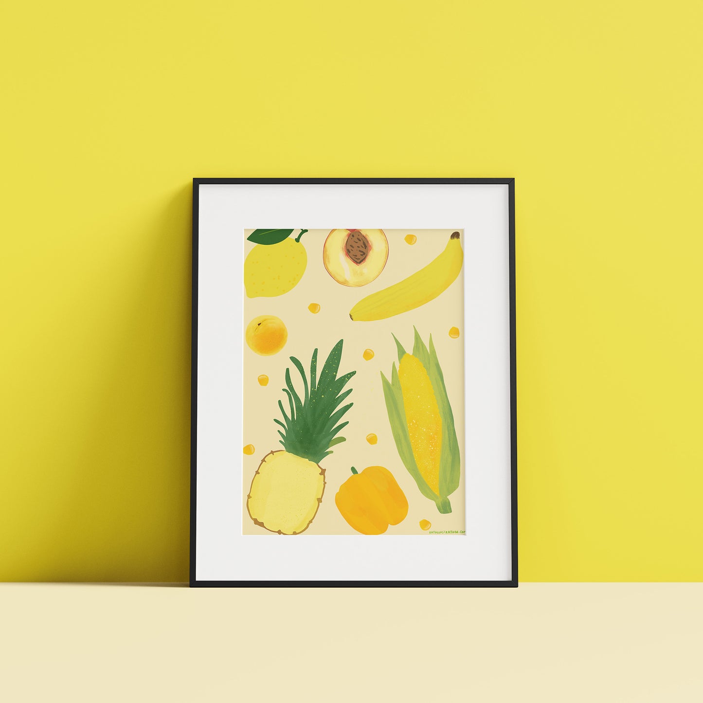 Image of a framed art print of yellow fruit and vegetables on a pale yellow background.