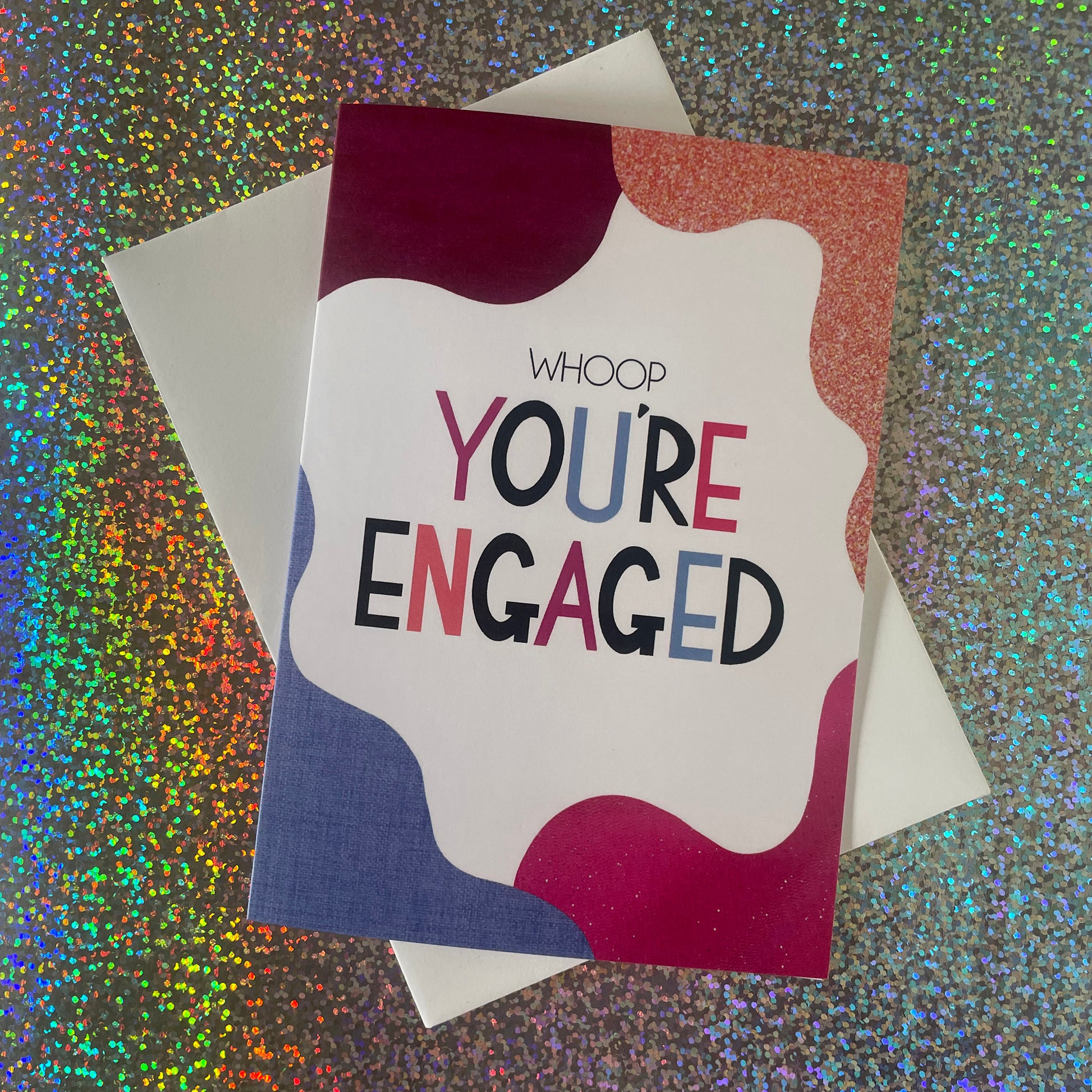 Image shows a bright greetings card with colourful, abstract shapes around the edge and the wording "Whoop you're engaged""