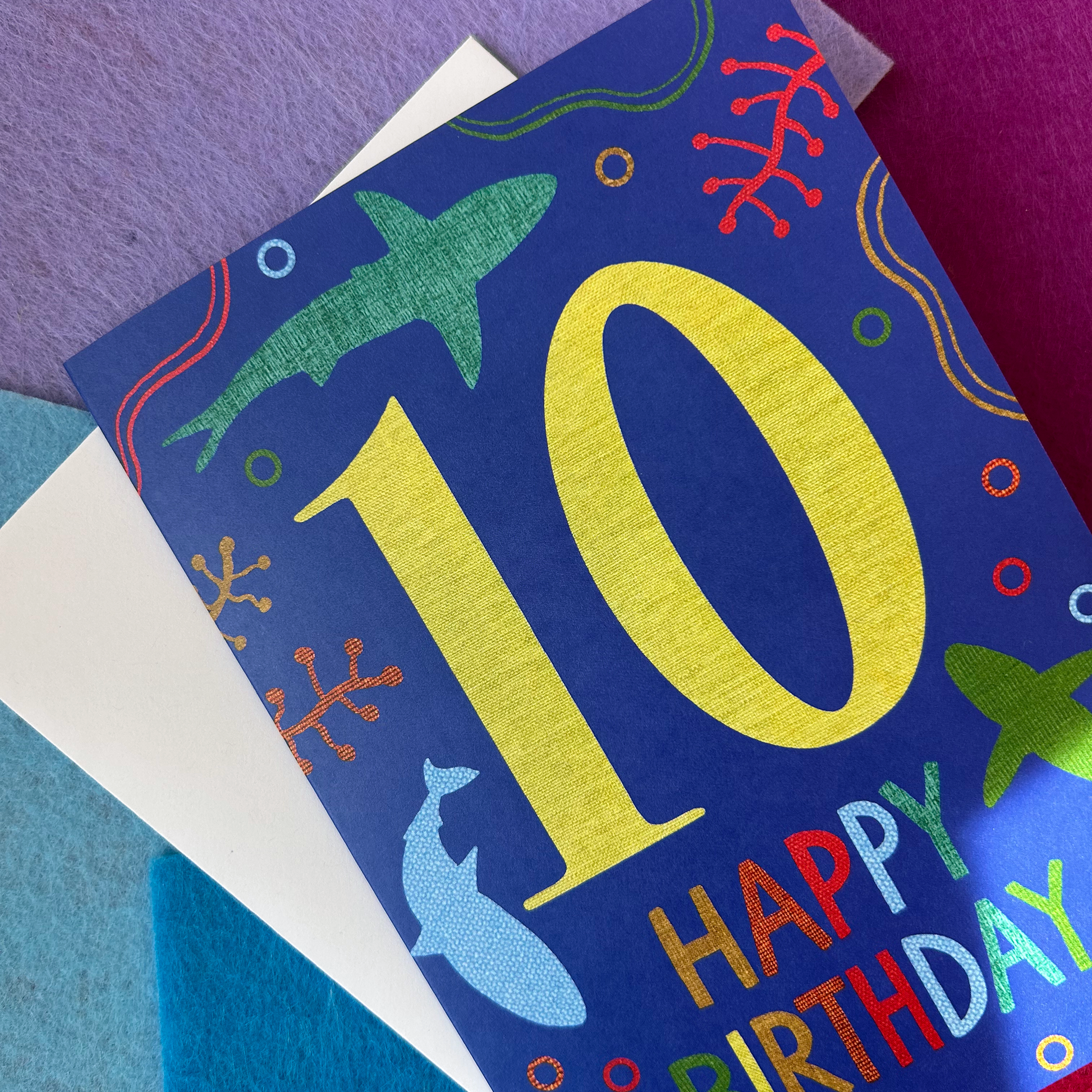 Colorful birthday card with number 10 and ocean-themed illustrations on a textured surface.