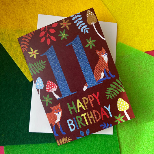 Birthday card with foxes and colourful text on a multicoloured background