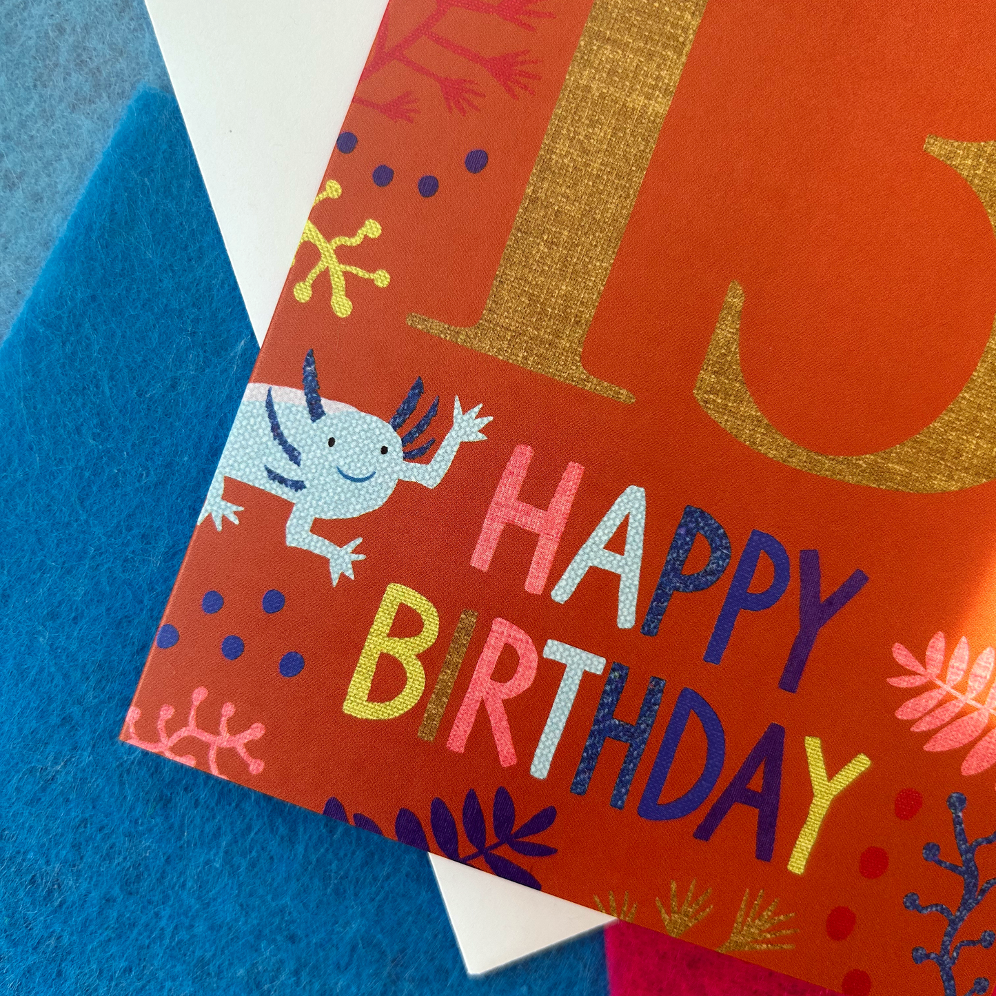 Birthday card with colourful text and an Axolotl illustration on a blue background