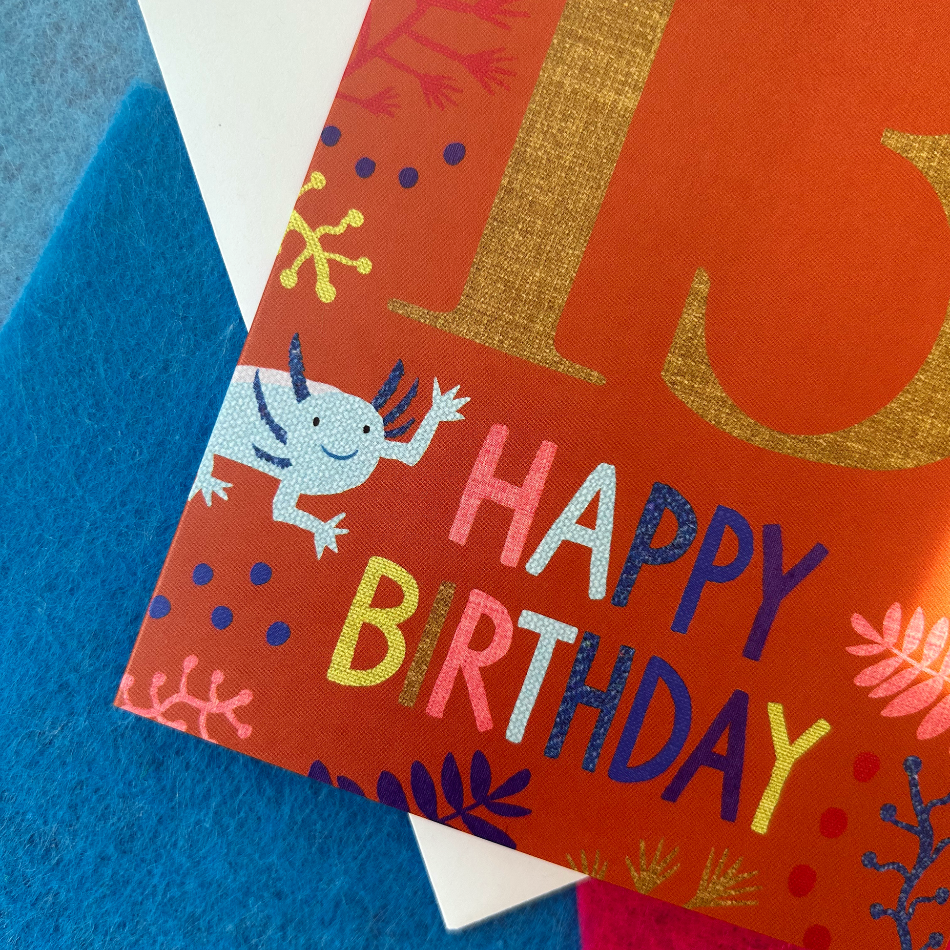 Birthday card with colourful text and an Axolotl illustration on a blue background