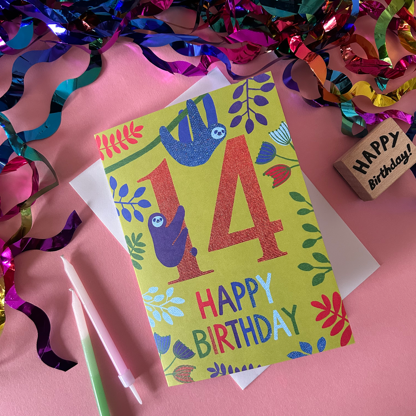 Birthday card with sloth design and 'Happy Birthday' text on a pink background with colorful streamers.