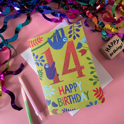 Birthday card with sloth design and 'Happy Birthday' text on a pink background with colorful streamers.