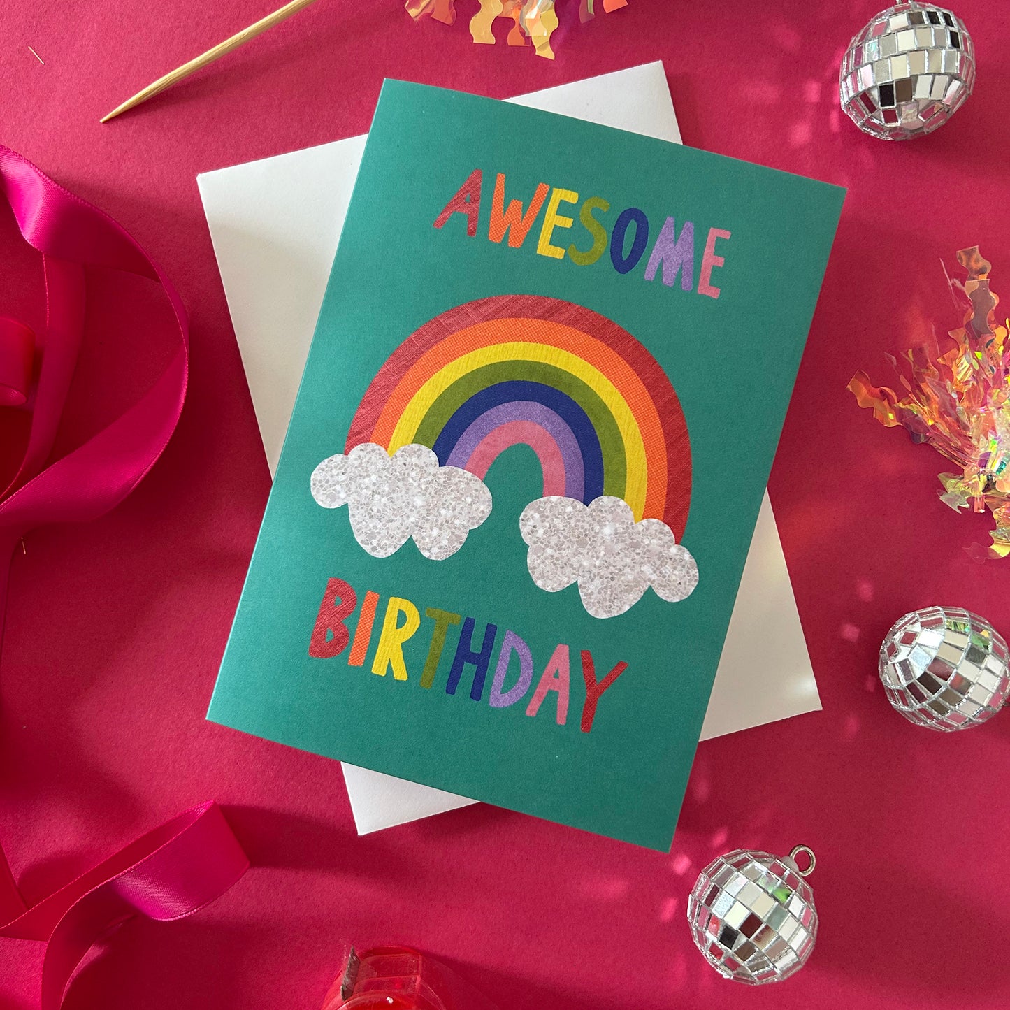 Birthday card with rainbow and clouds on a pink background