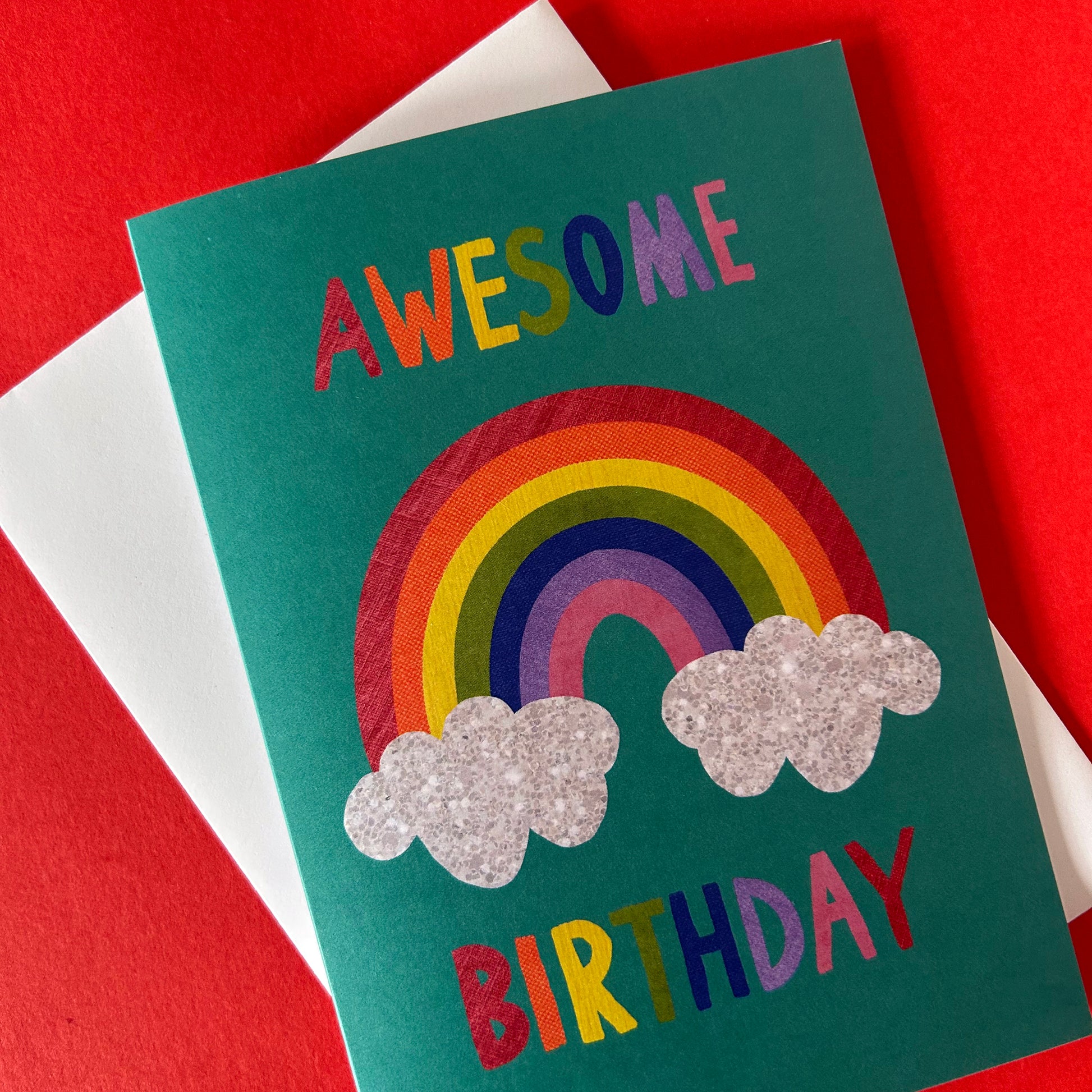 Birthday card with rainbow and clouds design on a red and white striped background