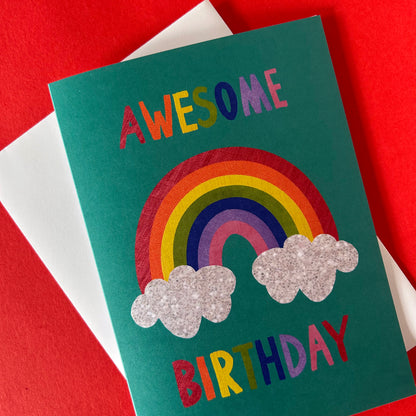 Birthday card with rainbow and clouds design on a red and white striped background