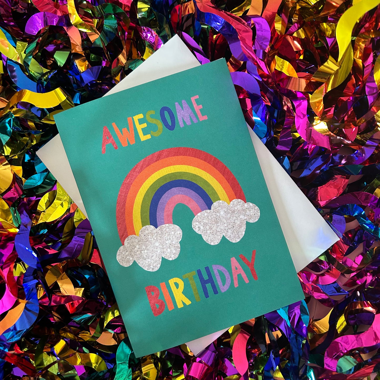 Birthday card with rainbow and clouds on a colourful confetti background