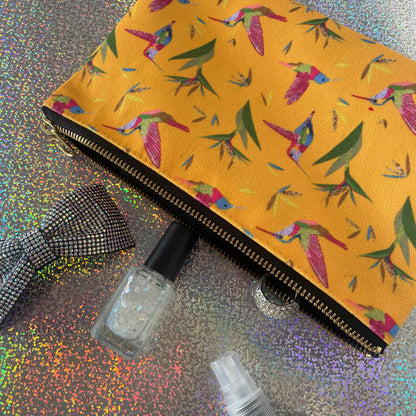 Image shows a bright yellow zip pouch with a colourful hummingbird and bird of paradise plant print.