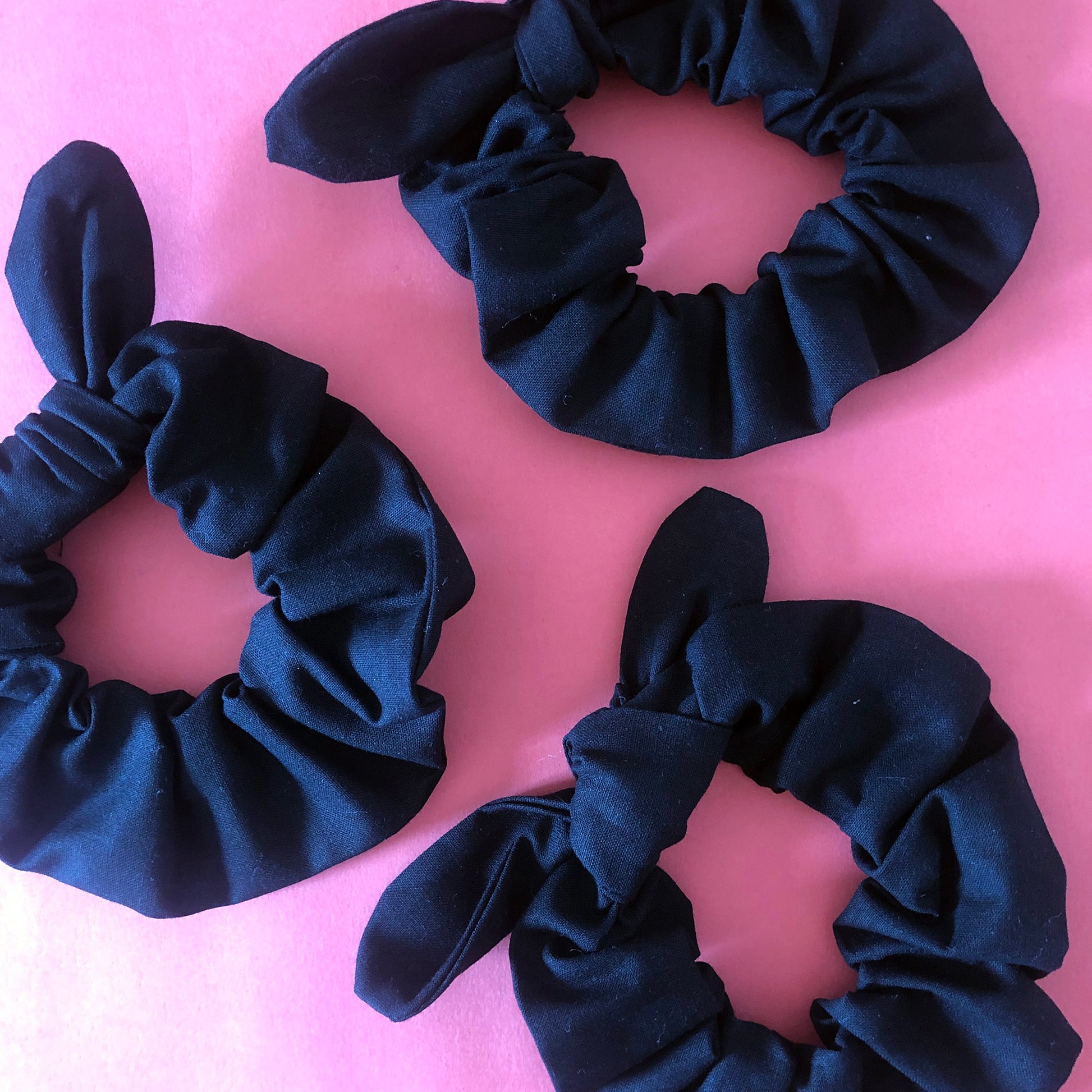 Image shows a black cotton hair scrunchie with a knot and bow