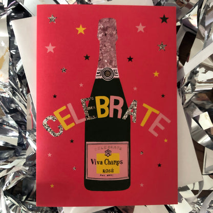 Image shows a bright red celebration card featuring a champagne bottle and stars