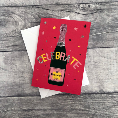 Image shows a bright red celebration card featuring a champagne bottle and stars