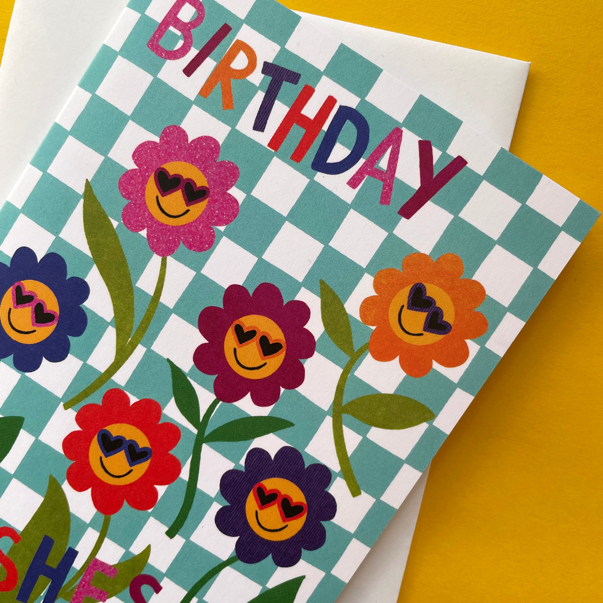Birthday card with colorful flowers and checkered pattern on a yellow background