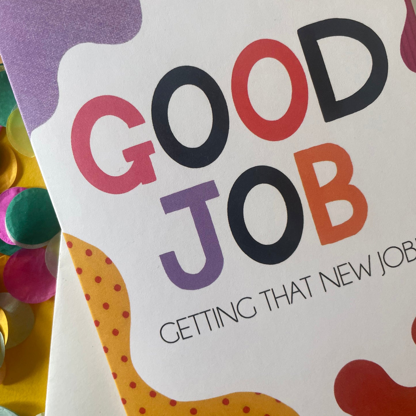 Image shows a bright greetings card with colourful, abstract shapes around the edge and the wording "Good Job getting that new job!"