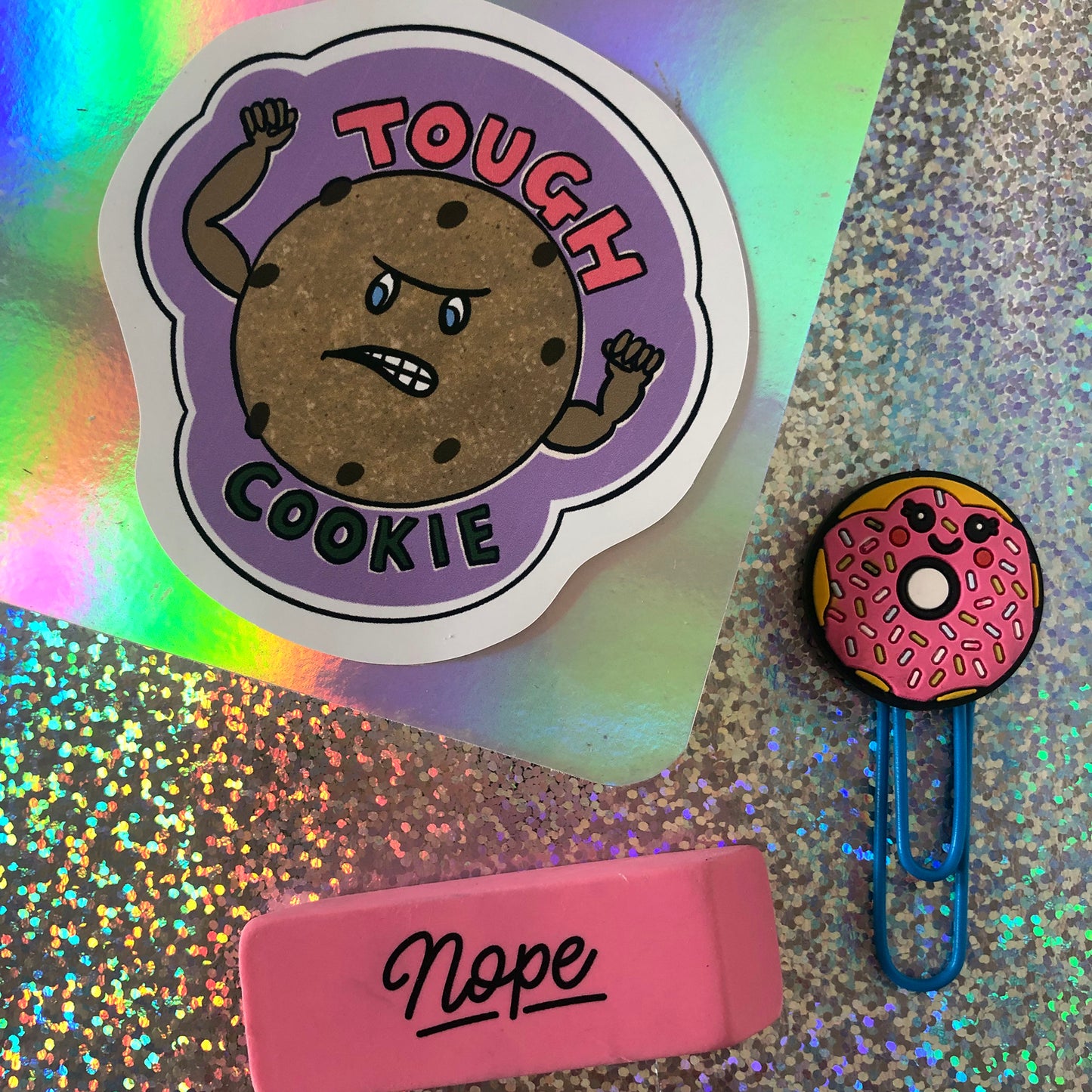 Image shows a vinyl sticker featuring an illustration of a cookie with muscles and the wording 'Tough Cookie'