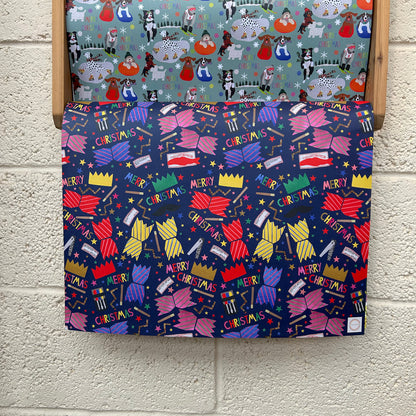 Christmas-themed patterned wrapping paper with bright, colourful Christmas Cracker design on a wooden rack.